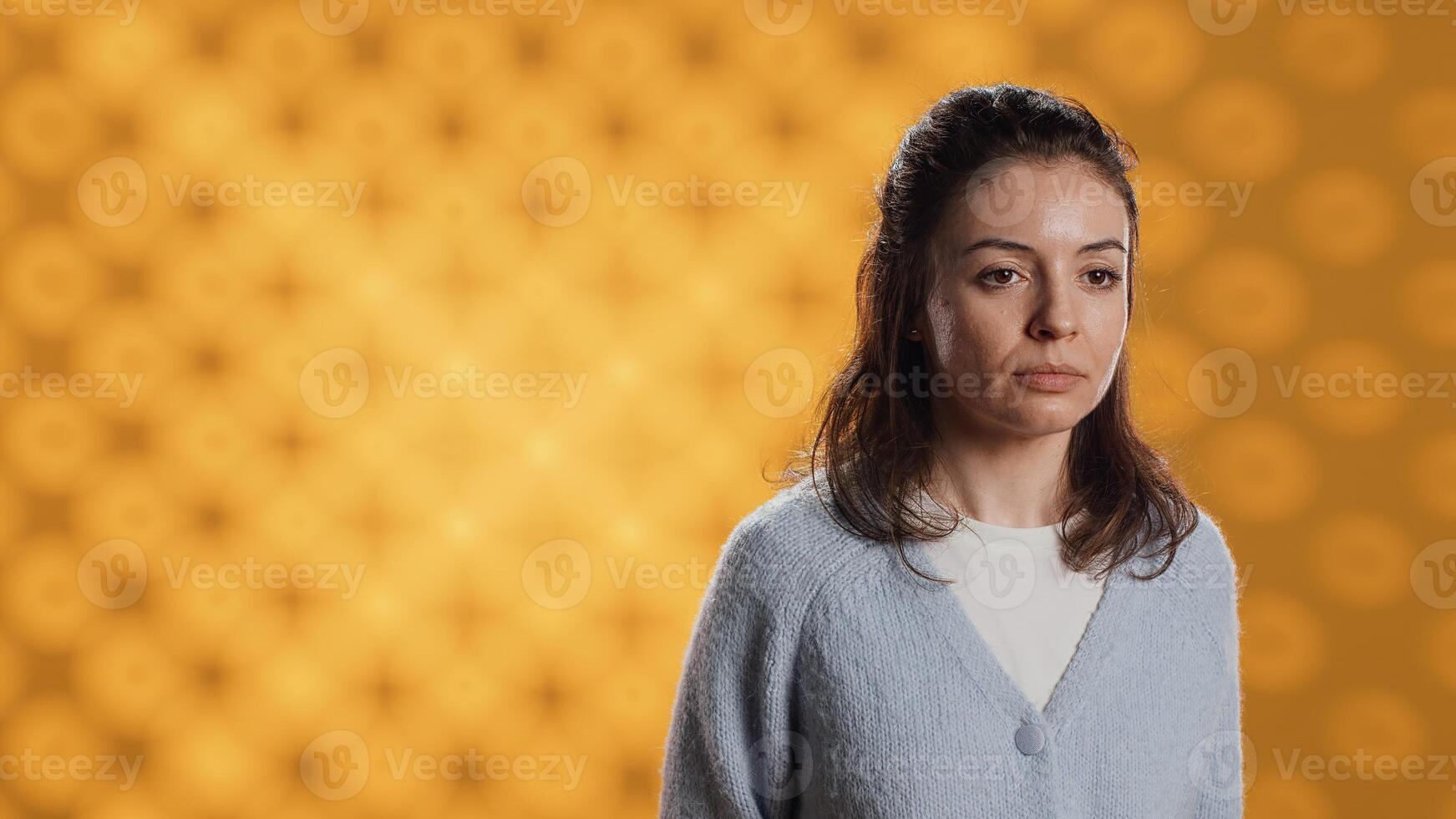 Portrait of relaxed woman posing, looking at camera, isolated over yellow studio background. Caucasian person dressed in casual attire standing, feeling confident, camera A photo