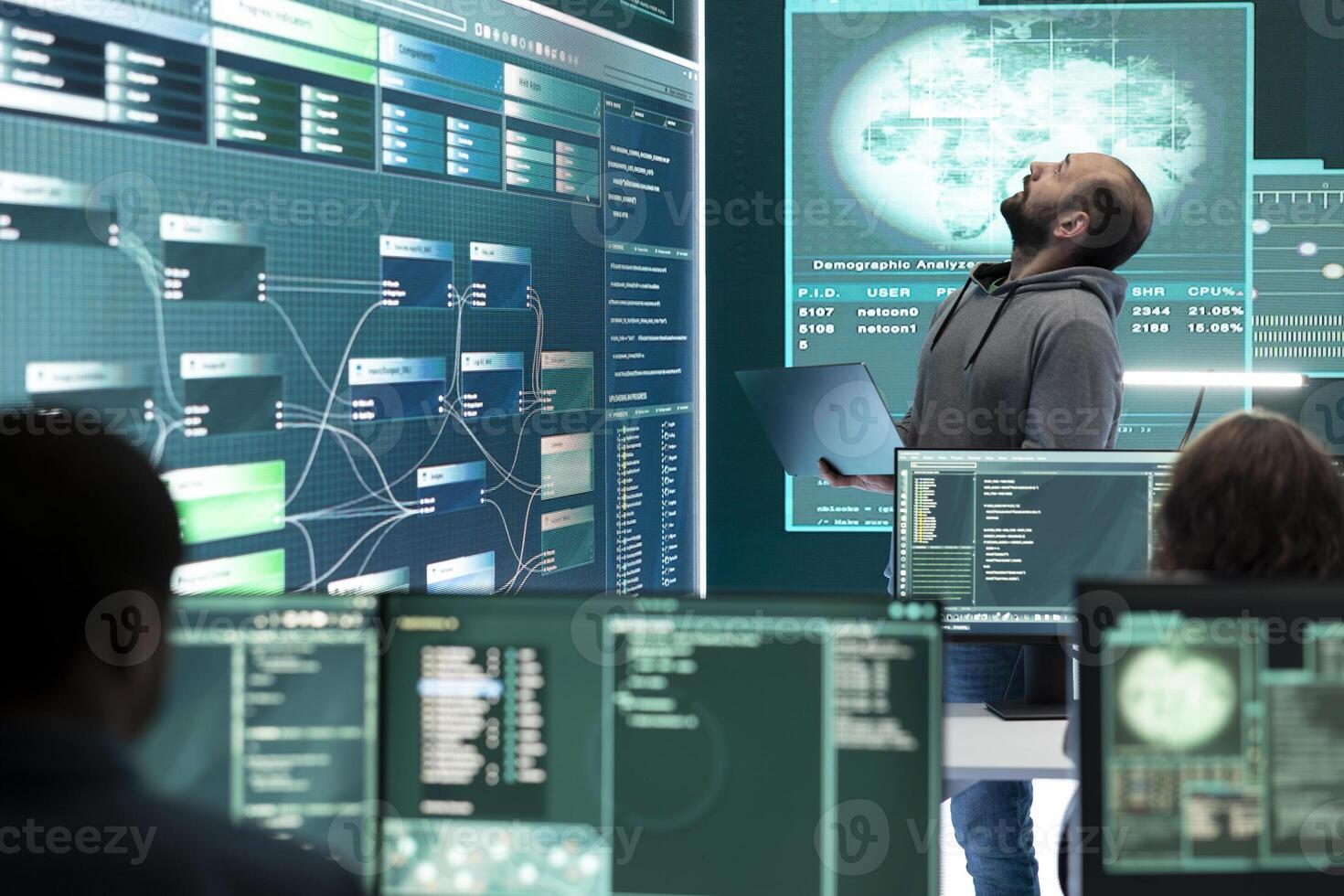 Hacker specialist working on governmental cyber surveillance in agency center, examining stolen information on a big screen during hybrid war. IT expert works on intelligence espionage. photo