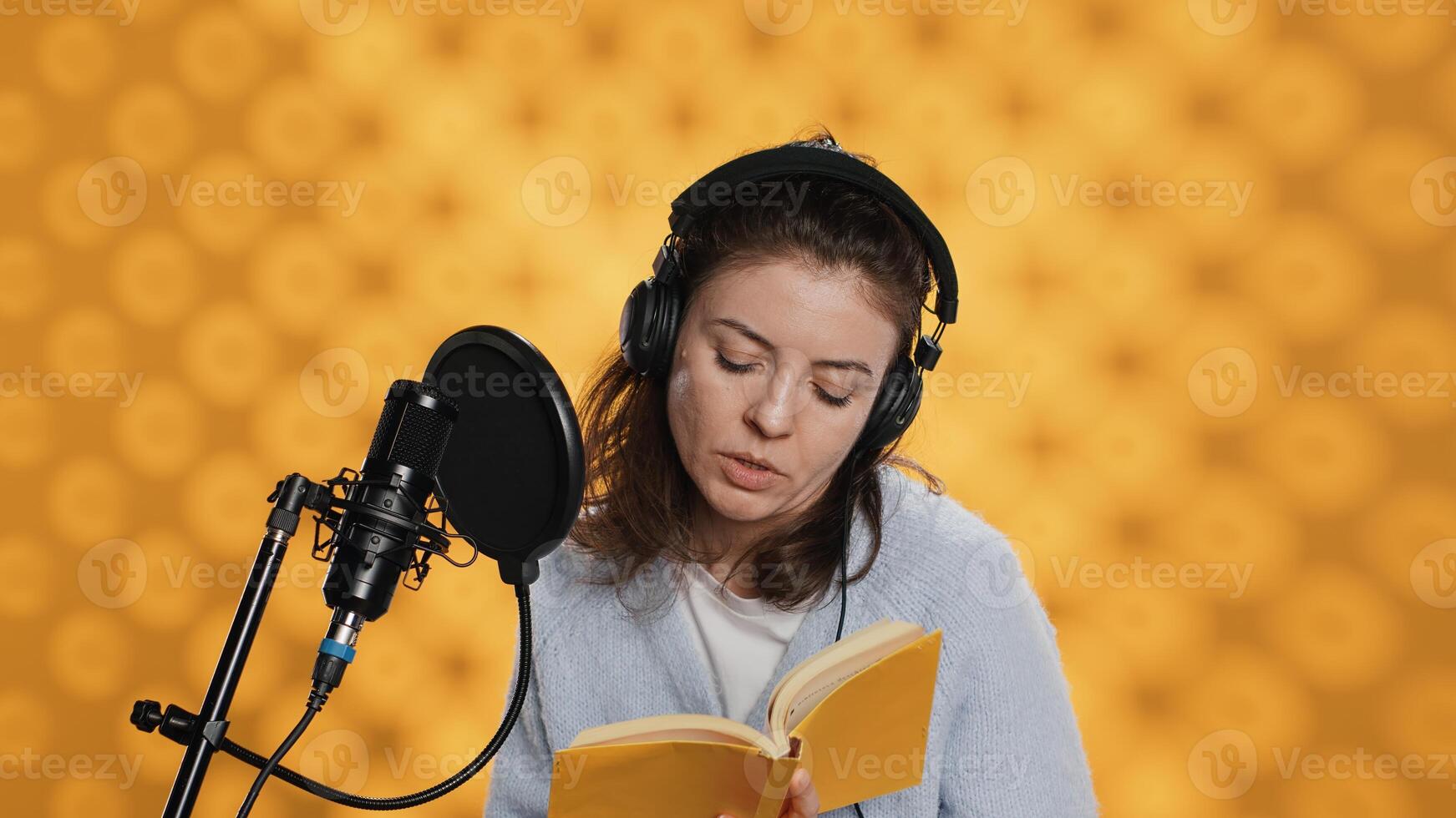 Lady browsing pages, doing voiceover reading of book to produce audiobook. Voice actor preparing to use storytelling skills to entertain audience while recording novel, studio background, camera A photo