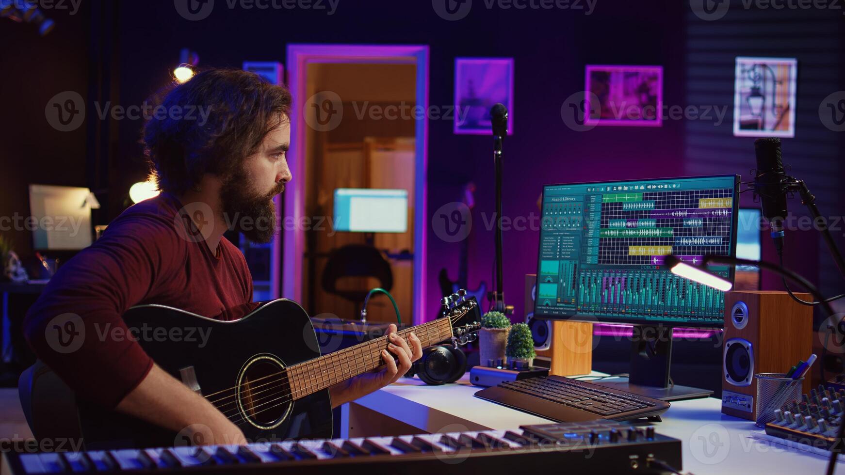 Music producer mixing guitar sounds played by him on acoustic instrument, using electronic soundboard console and daw software. Skilled musician developing new tunes, home studio. Camera B. photo