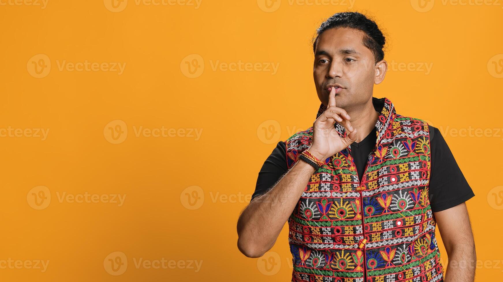 Annoyed indian man doing shushing hand gesturing, irritated by noise, having negative mood. Person placing finger on lips, doing quiet sign gesture, studio background, camera A photo