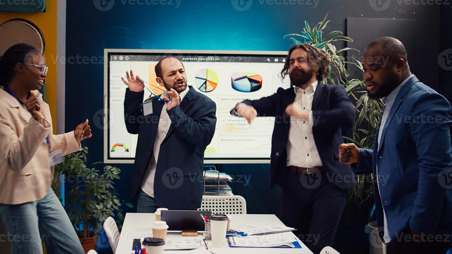 Satisfied coworkers dancing in the boardroom and celebrating a business development success. Employees feel excited and happy about their performance, helping organization grow. Camera A. photo