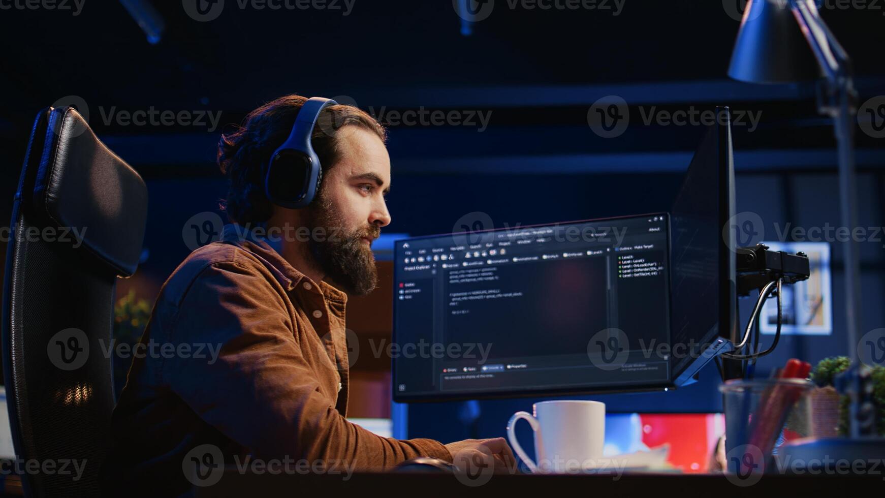 Cheerful programmer listening music while doing web development during remote job shift in neon lit home office, finishing coding project. IT expert enjoying audio podcast, working on PC, camera B photo