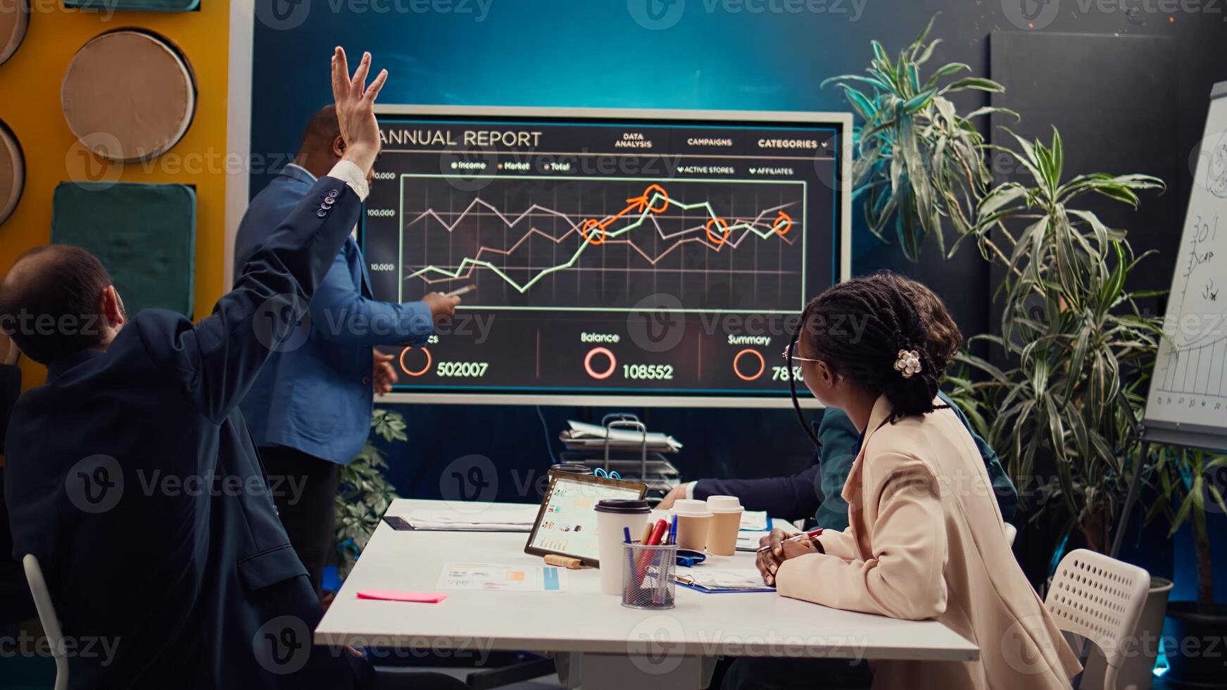 Diverse colleagues reviewing monthly sales infographics on interactive board, measuring feedback on previous initiatives for future improvements. Management team in a meeting. Camera B. photo