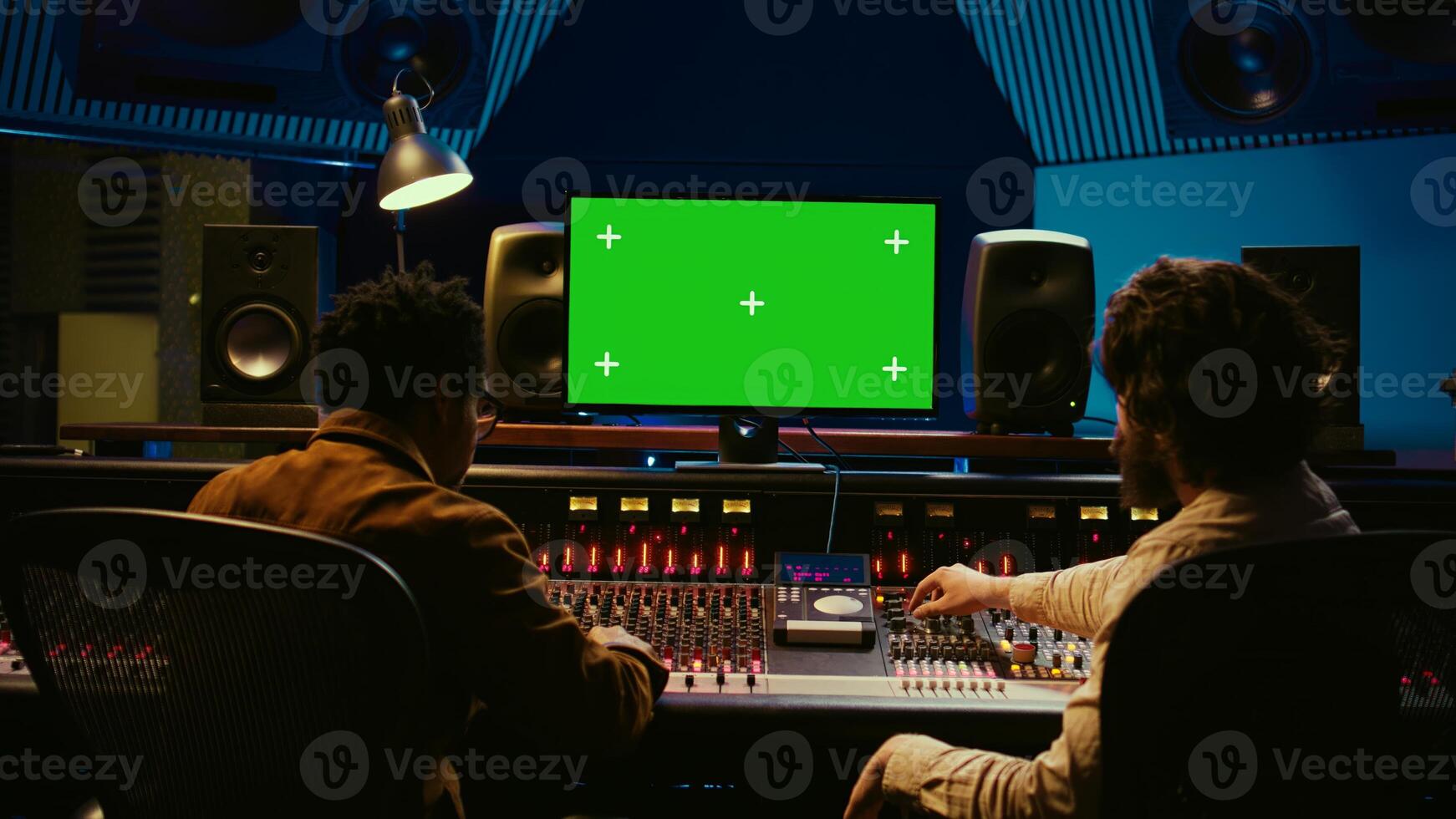 Diverse producers mixing and mastering tracks with mockup display on computer, recording before adding effects in post production. Artist and sound engineer twisting control desk knobs. Camera B. photo