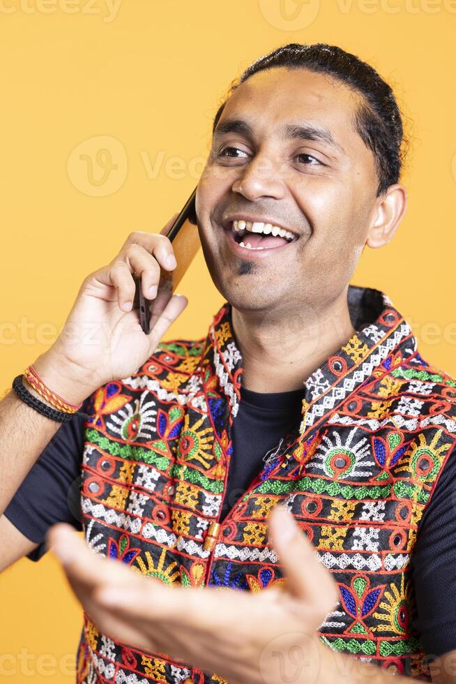 Happy man cracking jokes with best friend over telephone call using smartphone. Overjoyed person talking with mate in phone call using mobile phone, being entertained, studio background, close up shot photo