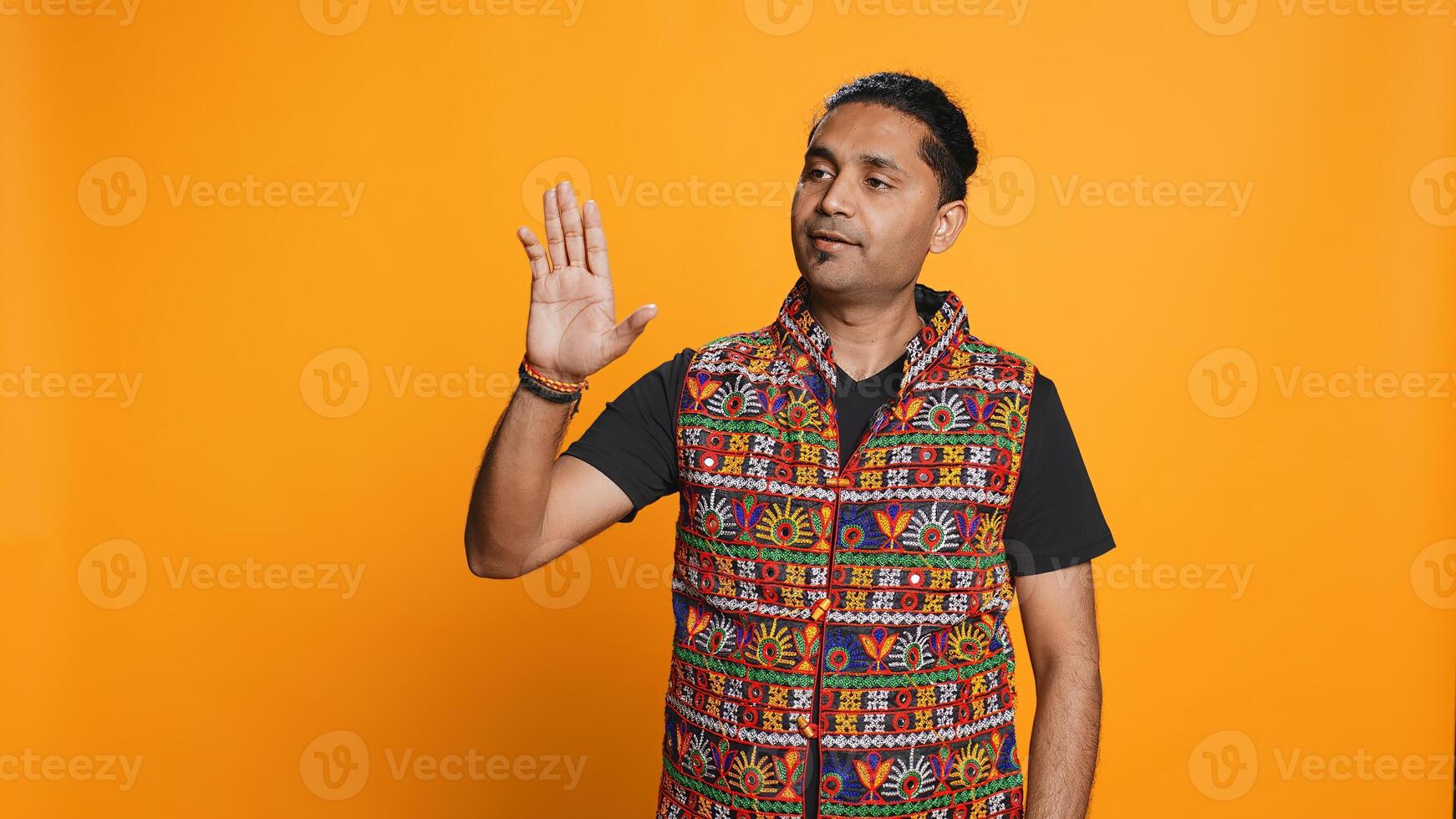 Indian man trying to stop chaotic fight using calming hand gesture to diffuse tensions, doing peaceful resolution. Reassuring person doing calm down sign gesturing, studio background, camera B photo