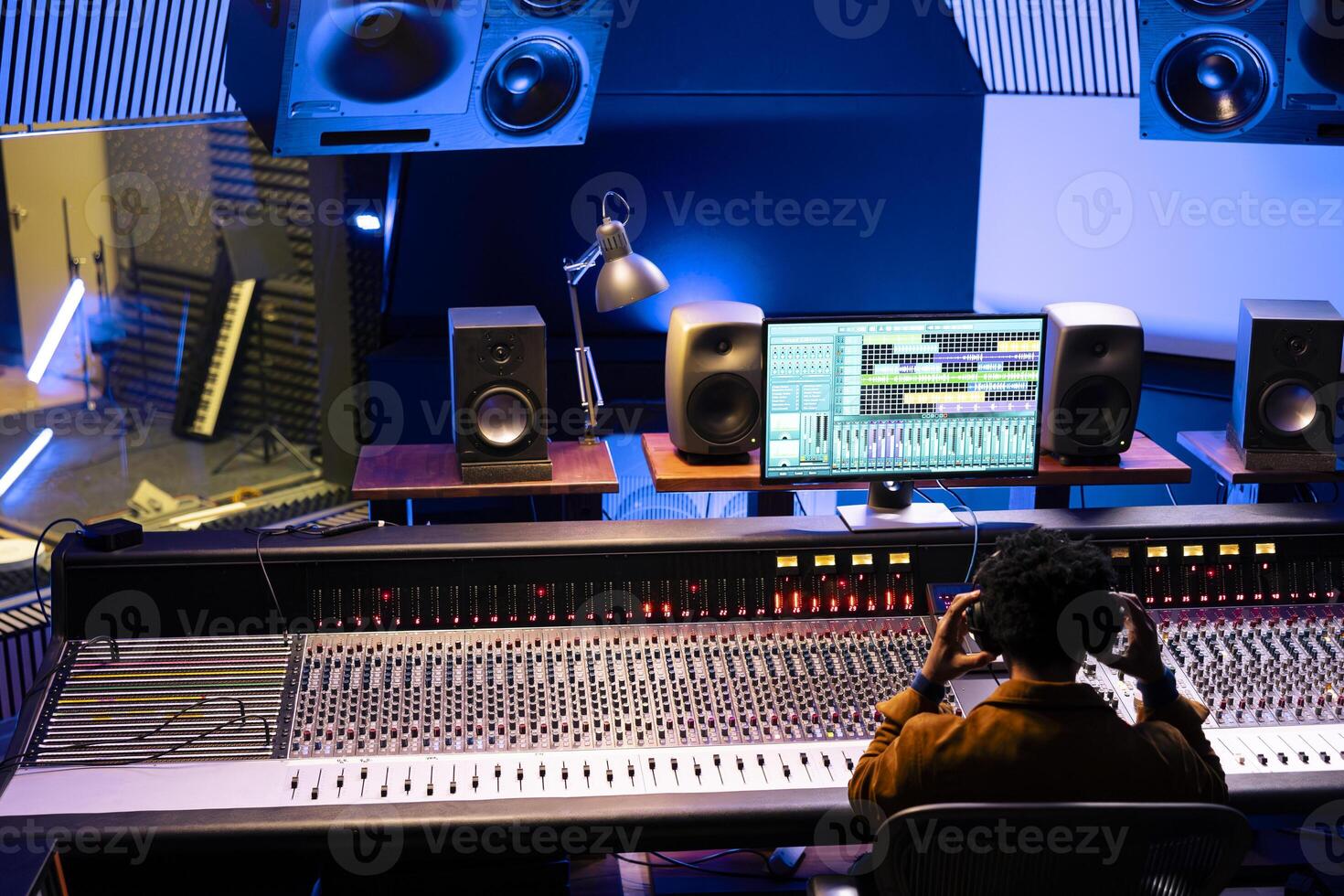 African american sound designer editing records in professional studio, working on mix and master tracks with control panel board desk. Skilled audio engineer producing new music, stereo gear. photo