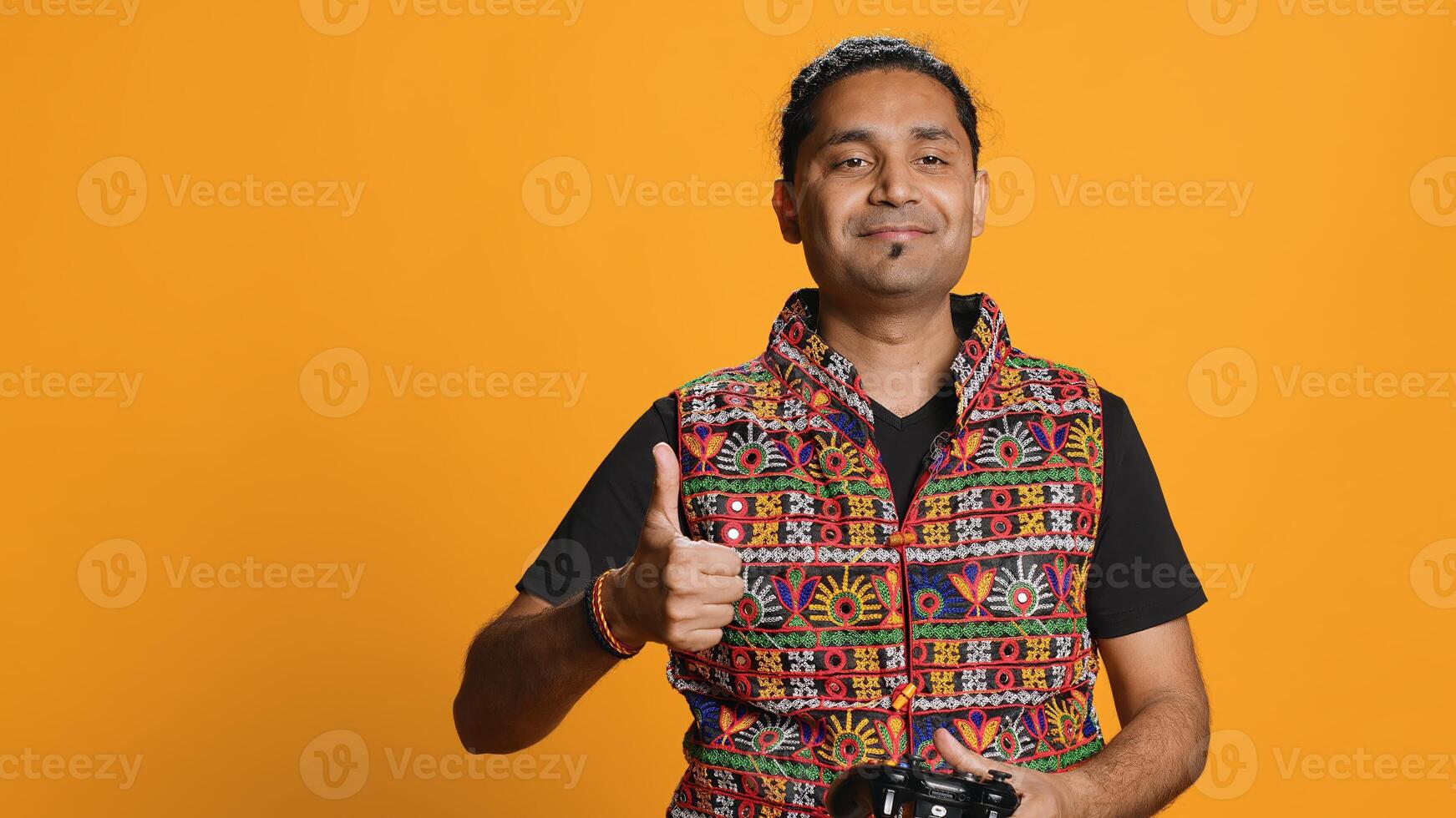 Gamer annoyed after losing online multiplayer videogame, being defeated by rival players. Indian man shocked and gutted after seeing game over message, holding controller, studio background, camera A photo