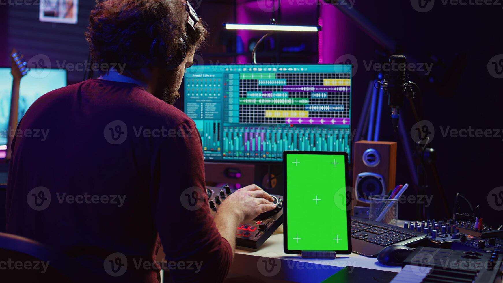 Music producer songwriter mixing tunes on stereo console, recording sounds next to tablet with greenscreen layout. Artist using equalizer and control panel board, daw software. Camera B. photo
