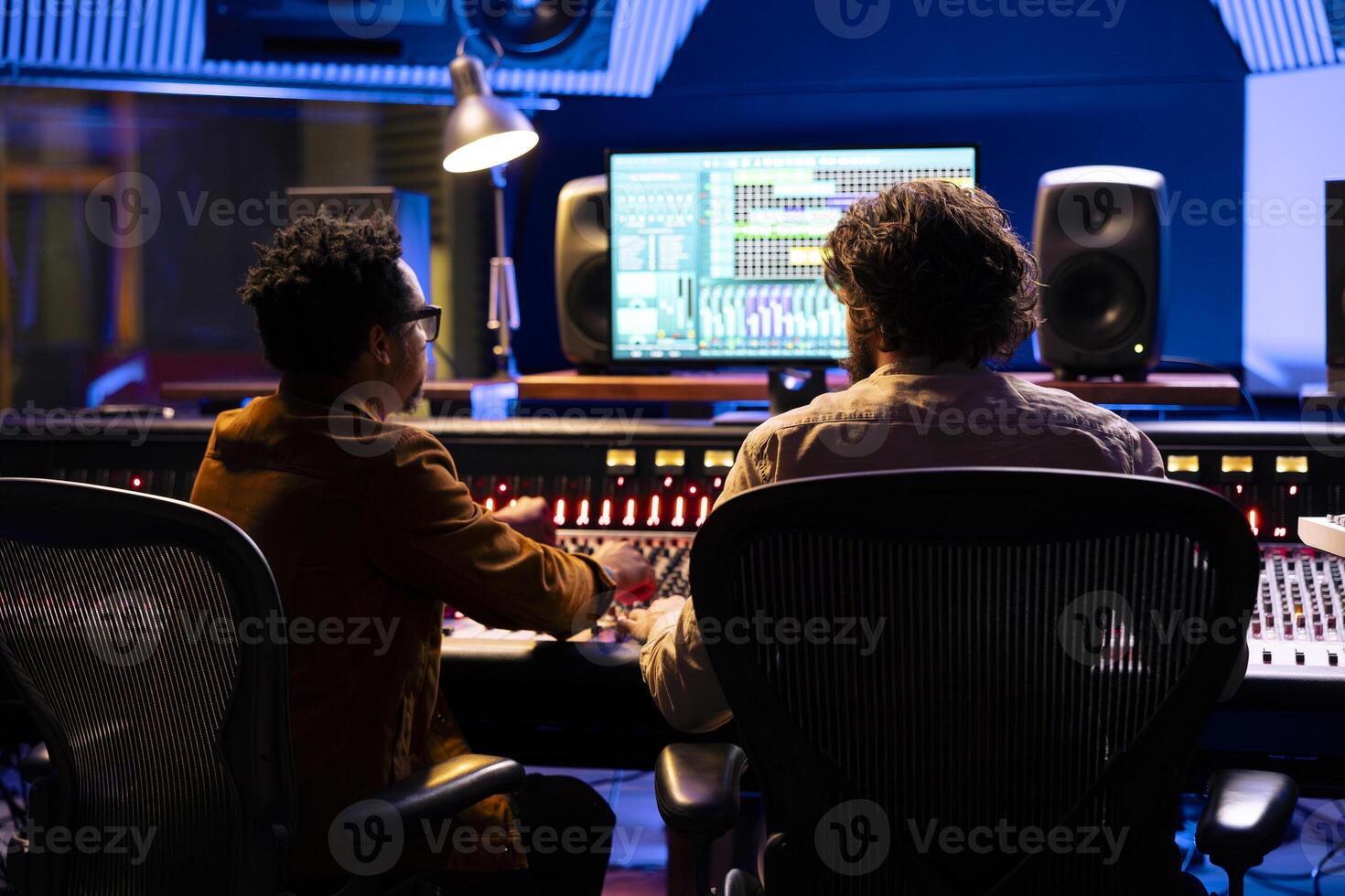 Team of artist and technician working on track recording in control room, mixing and processing songs with control panel board and technical equipment. Singer and sound designer producing tunes. photo