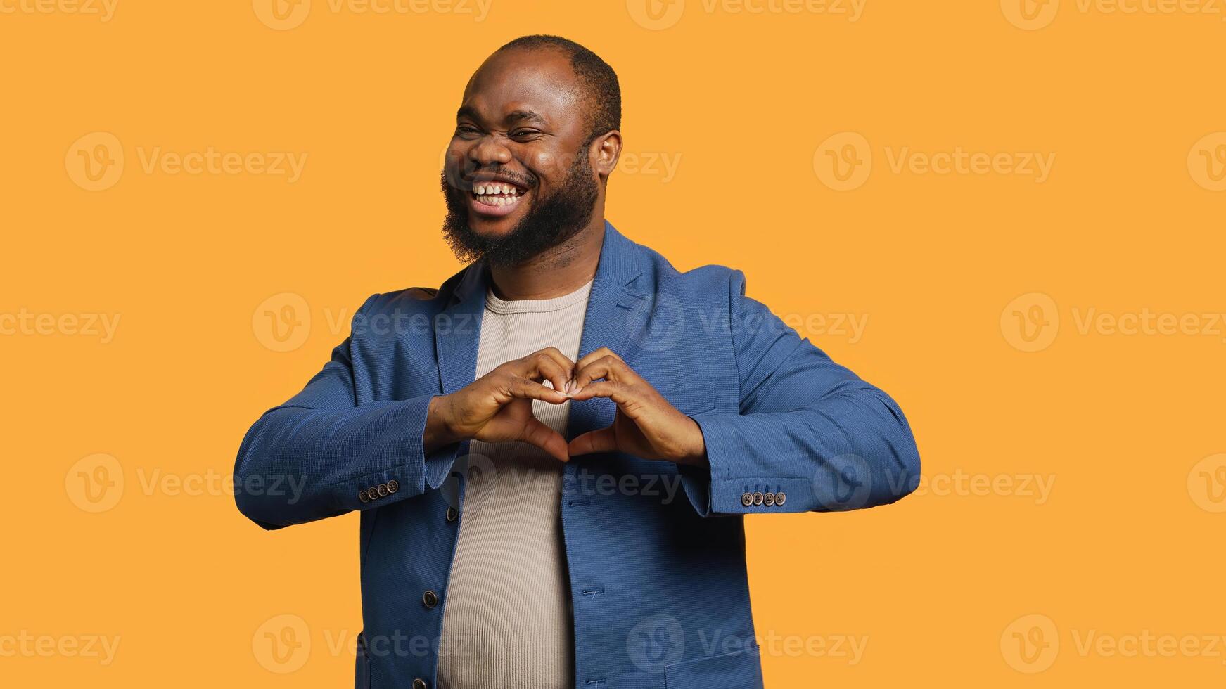 Portrait of jolly friendly african american man doing heart symbol shape gesture with hands. Cheerful nurturing BIPOC person showing love gesturing, isolated over studio background, camera A photo