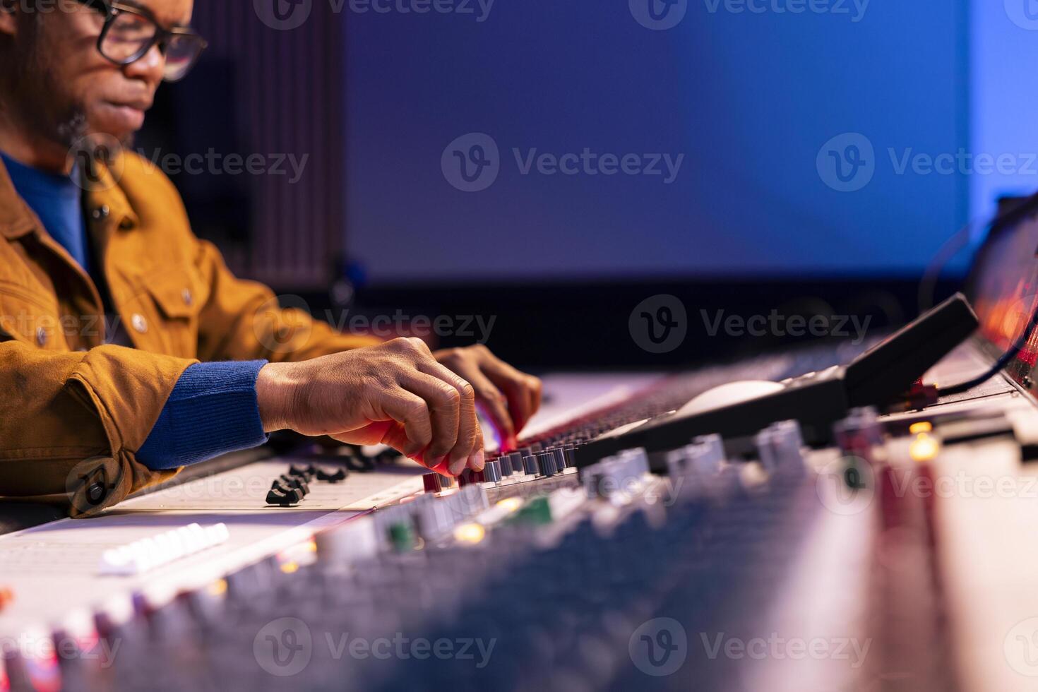 Audio engineer producing new tracks on console in control room, twisting knobs and pressing faders on soundboard panel. Music producer working on processing and editing music. Close up. photo