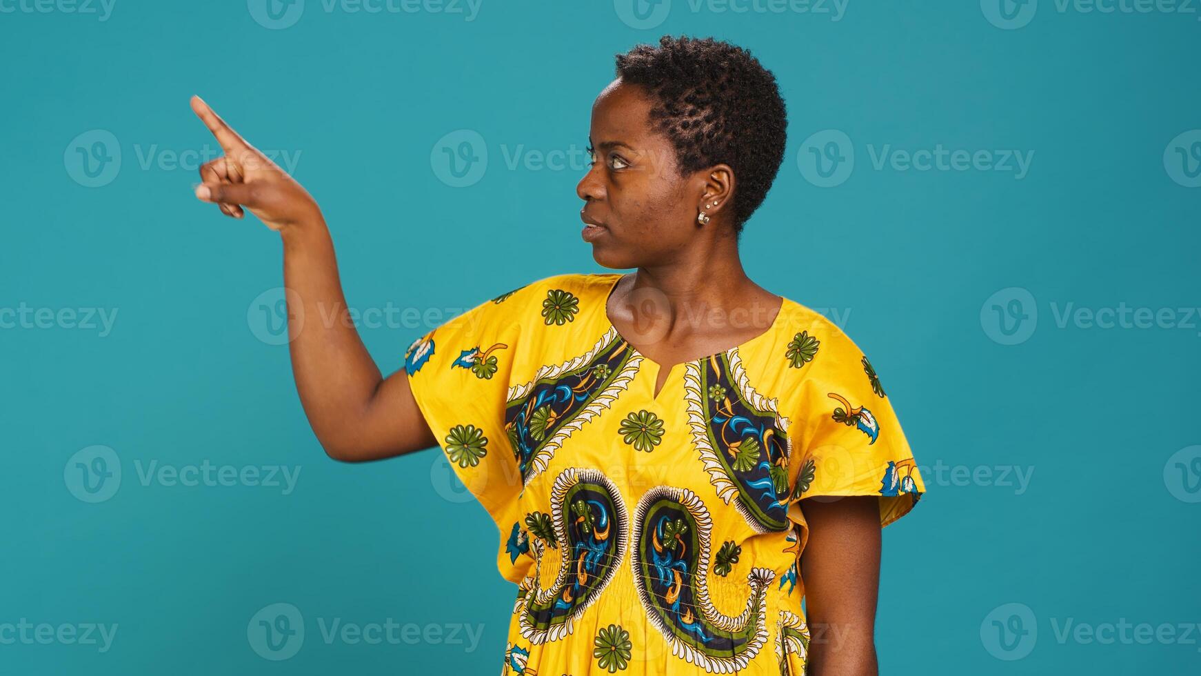 Young woman indicating direction to left or right in studio, pointing her index fingers aside. Confident natural person wears traditional ethnic clothes with floral native elements. Camera A. photo