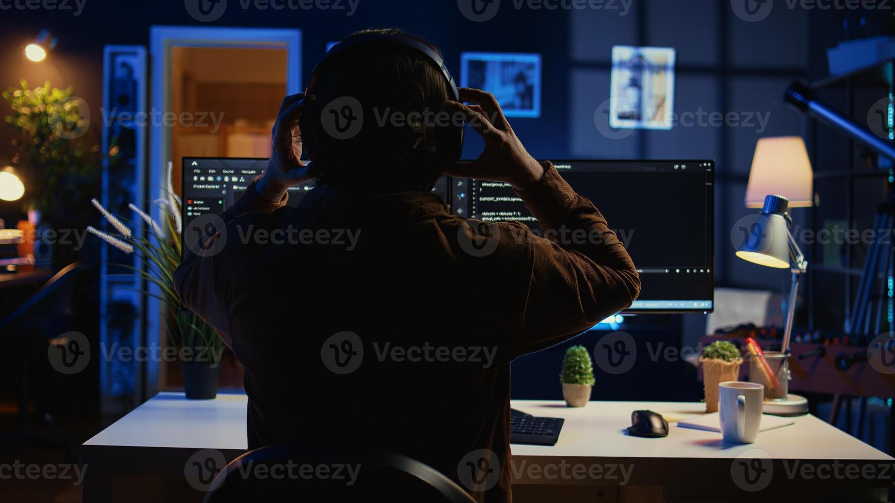 Technician putting headphones on while using coding to fortify firewalls, teleworking for IT company. Computer scientist listening music and upgrading binary code scripts in home office, camera B photo