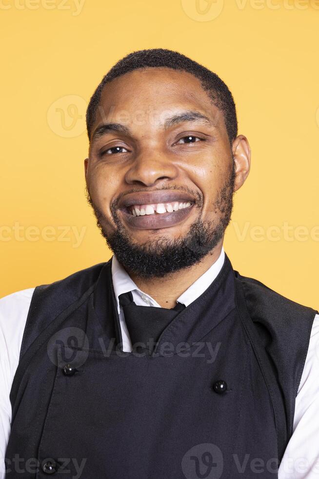Portrait of professional server posing with confidence with arms crossed in studio, wearing his five star restaurant uniform and serving people. Waiter with customer focused duty. photo