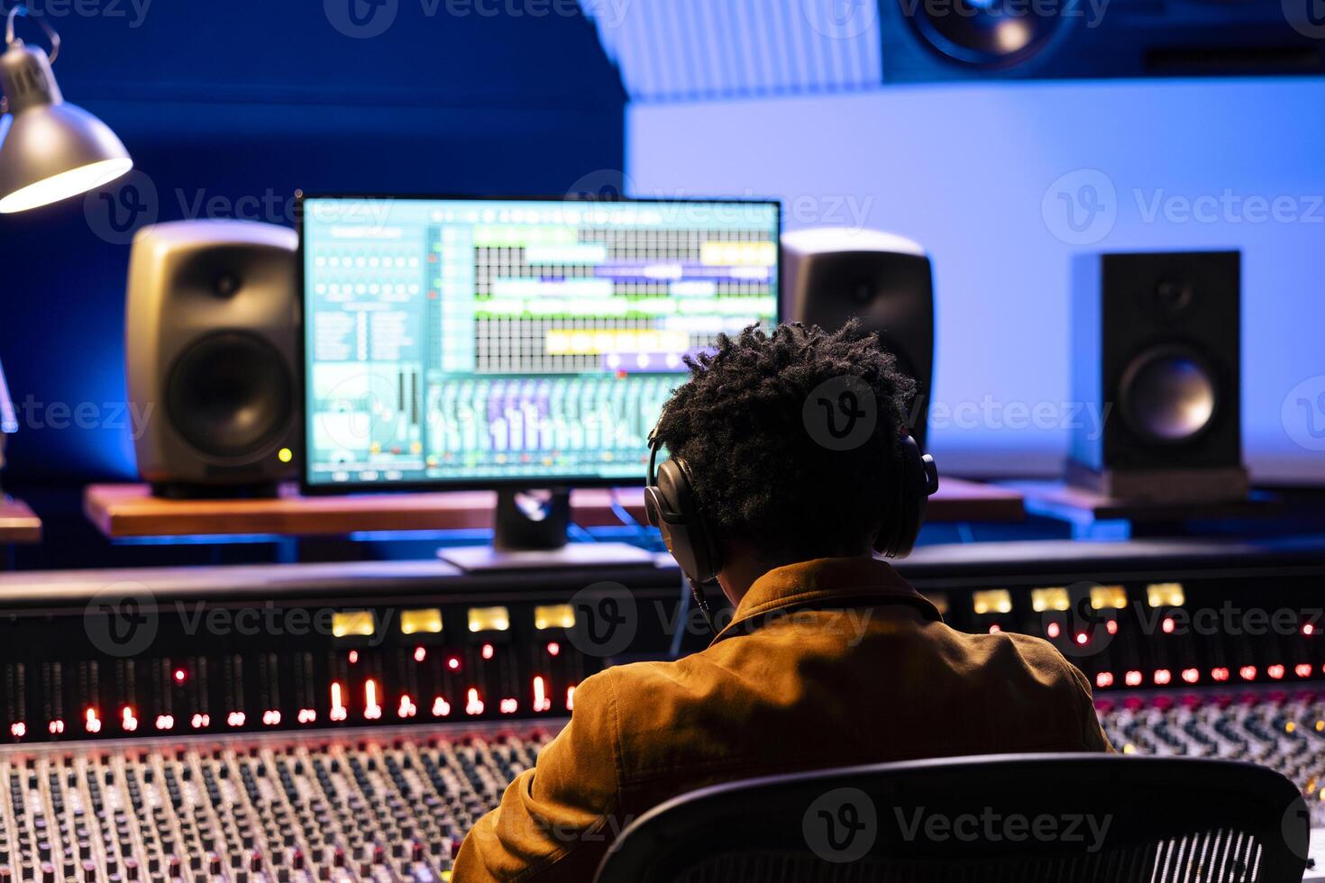 African american sound engineer editing tracks in control room at studio, working on mixing and mastering tunes for a new album. Audio technician producing new records with technical equipment. photo