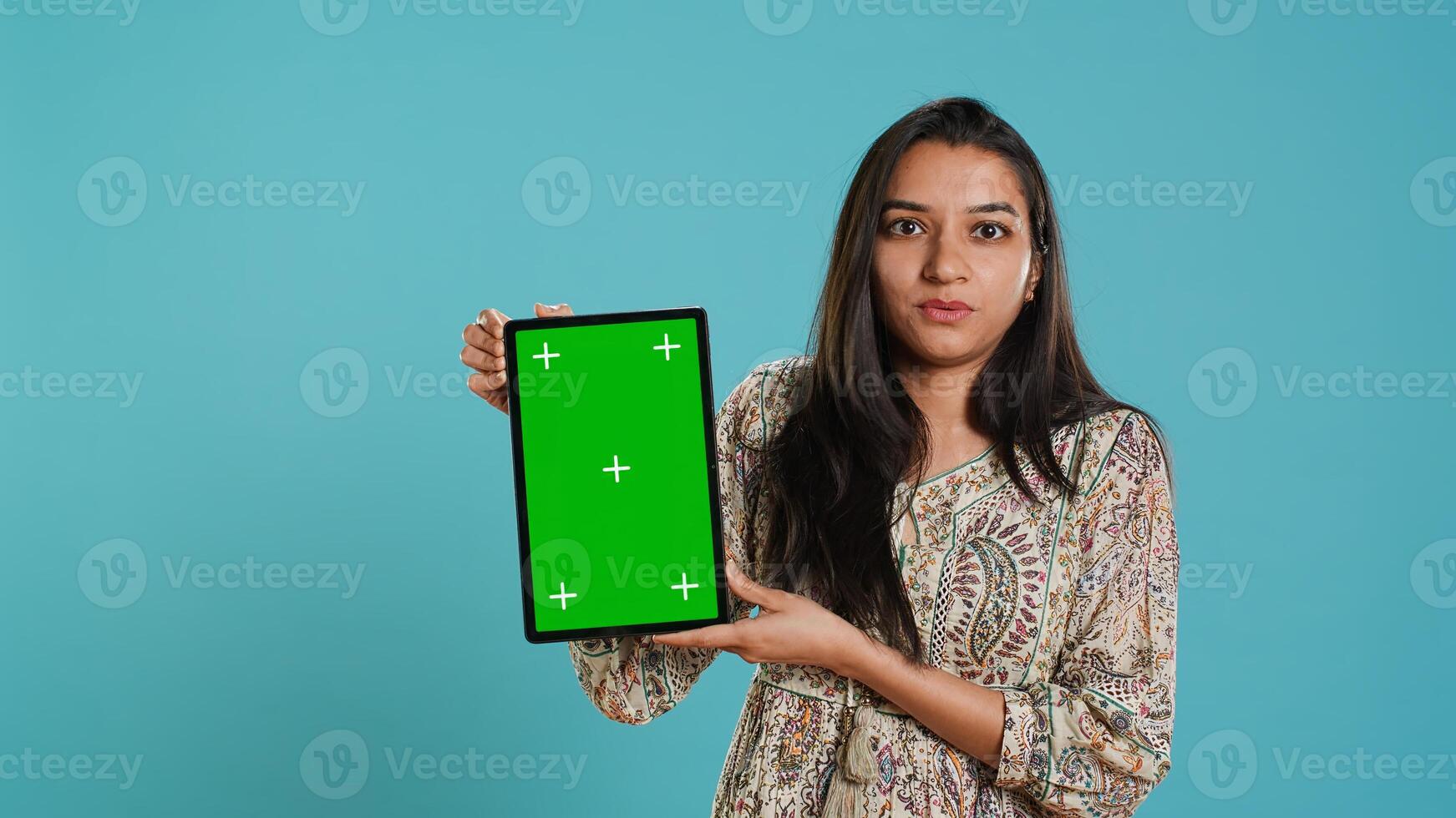 Person doing influencer marketing using isolated screen tablet, studio background. Indian woman holding empty copy space chroma key digital device, doing review, camera A photo