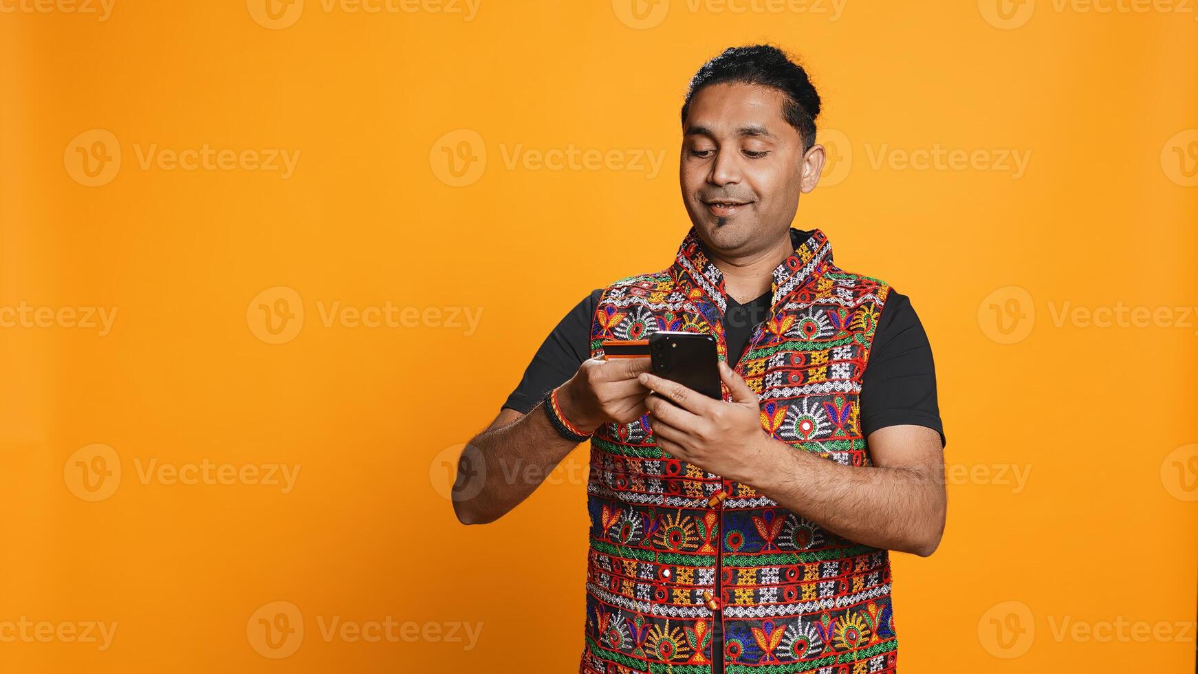 Man adding payment method on phone website, delighted to take advantage of promotions, studio background. Person thrilled to do internet shopping, typing credit card data on smartphone, camera B photo