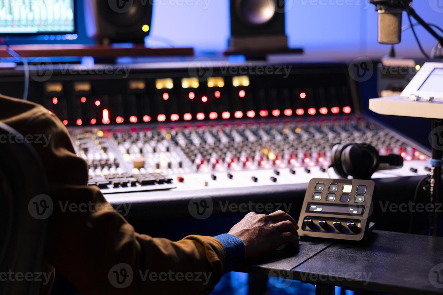 African american expert working at mixing panel in recording studio. Using control desk soundboard and digital audio software interface on pc, motorized faders and switchers to edit tracks. photo
