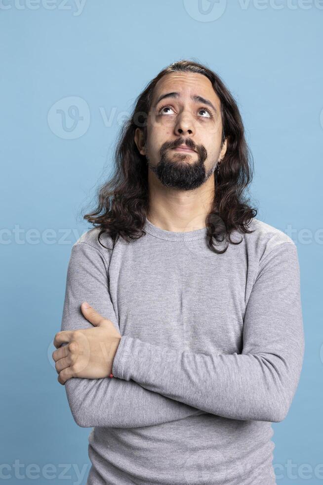 Uncertain pensive person rubbing his chin and contemplating about something, searching for ideas and being reflective. Curious young adult posing with a puzzled expression in studio. photo