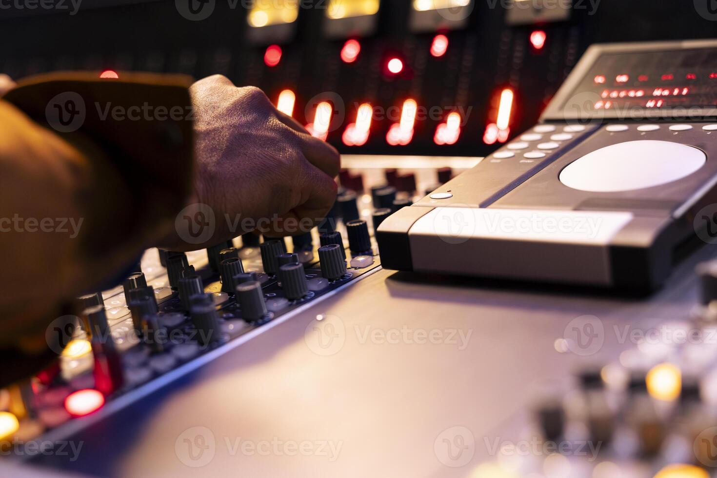 African american sound designer operates mixing console in control room, pushing sliders and buttons to adjust audio settings on records. Music engineer producing new tracks in studio. Close up. photo