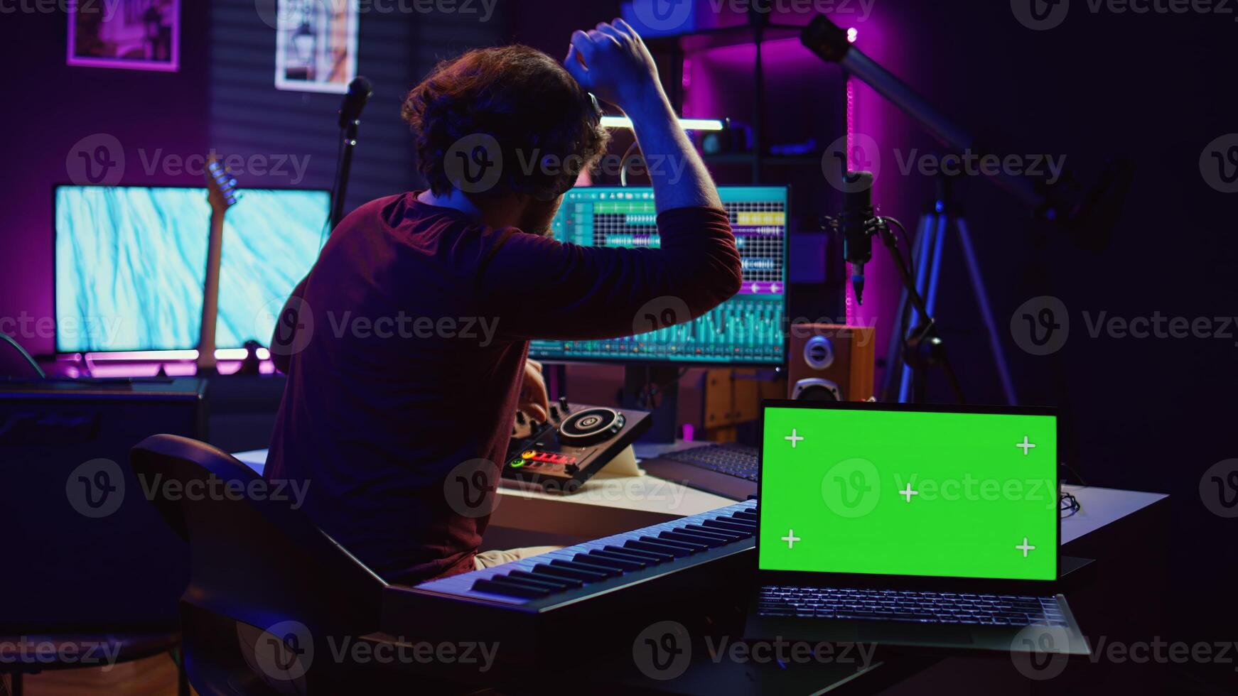 Musician mixing and mastering sounds at home studio with electronic console and soundboard, creating modern tunes. Sound engineer producing audio tracks with greenscreen on tablet. Camera B. photo