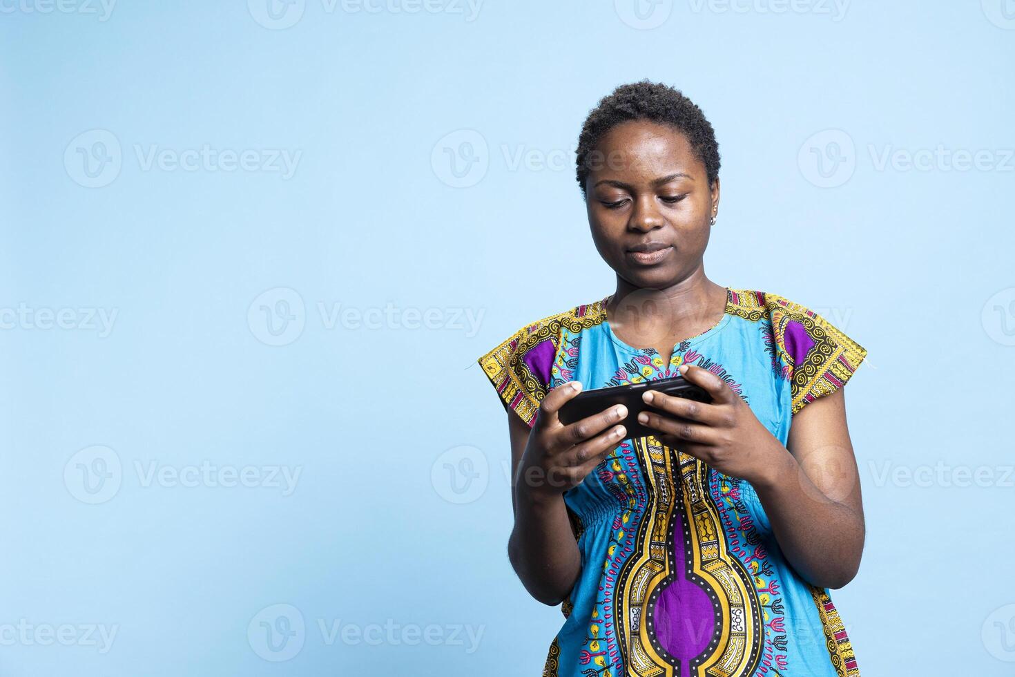 African american person having fun with videogaming play, using mobile phone to participate in cyber sport championship. Woman gamer playing virtual tournament in studio, gaming device. photo