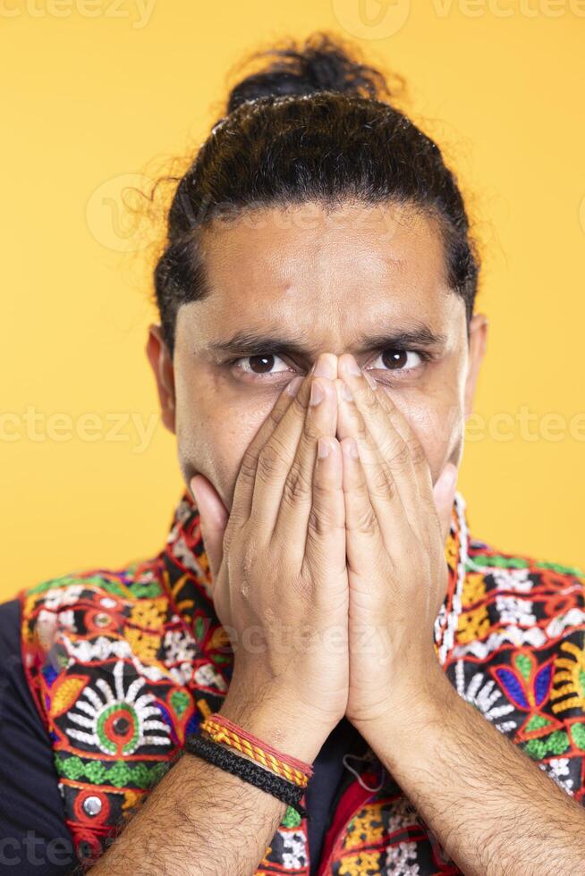 Portrait of troubled man covering mouth in disbelief, feeling saddened and rattled by events, isolated over studio backdrop. Close up shot of person on the verge of crying, left speechless by troubling news photo