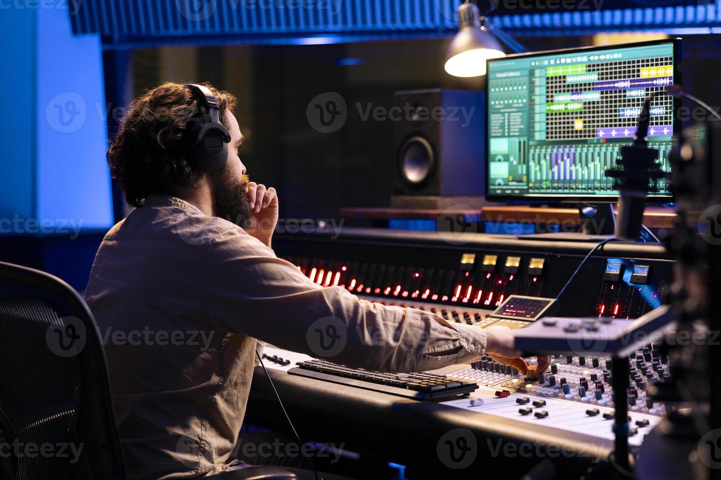 Audio expert operating on control desk with motorized faders and mixing console in professional studio, using sliders and knobs to process sounds. Music engineer producer recording tracks. photo