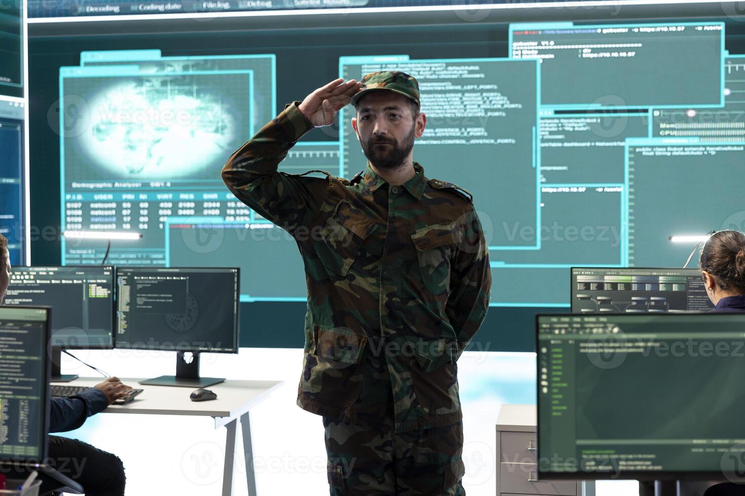 Army soldier showing the respectful military salute in government high tech agency, hackers in hybrid warfare strategies. People working with modern software and technology to secure information. photo