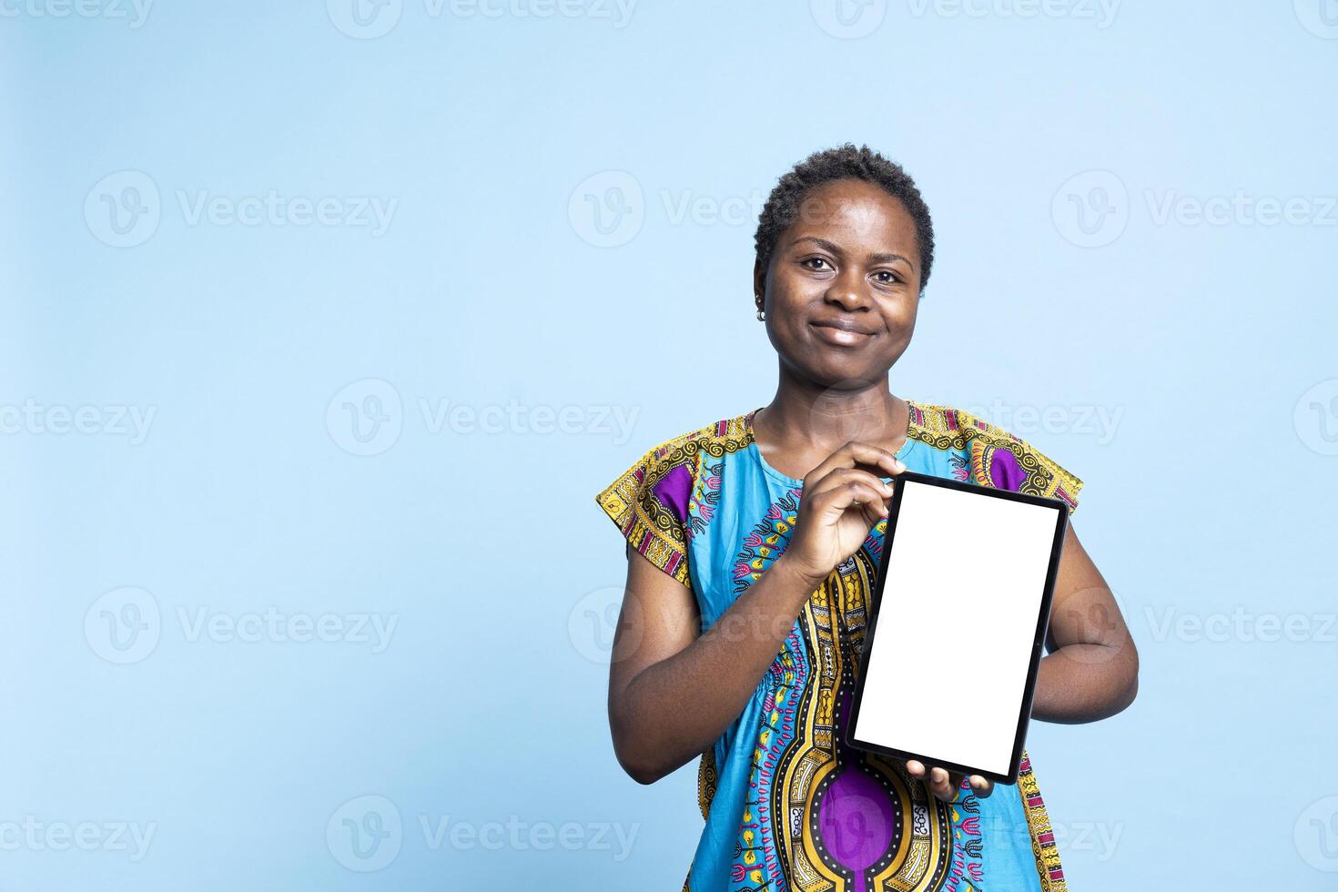 Confident woman showing tablet with blank mockup layout, creating advertisement with isolated copyspace template on wireless device. African american girl presents white display on camera. photo