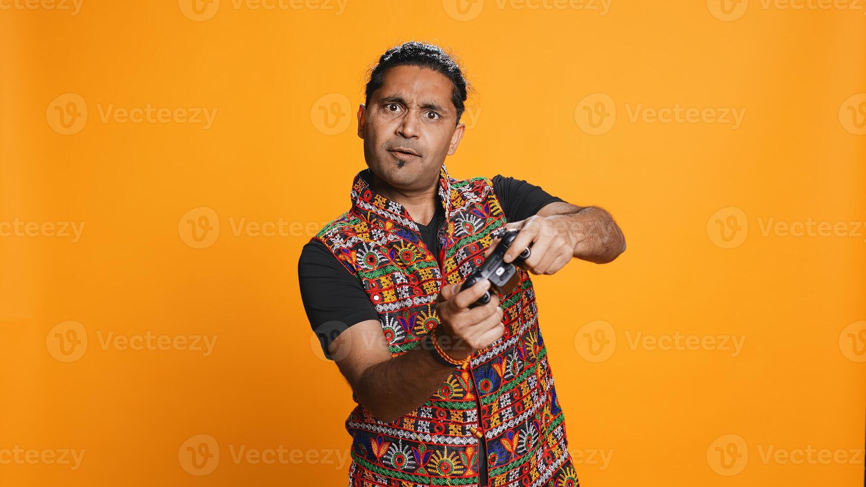 Gamer annoyed after losing online multiplayer videogame, being defeated by rival players. Indian man shocked and gutted after seeing game over message, holding controller, studio background, camera B photo