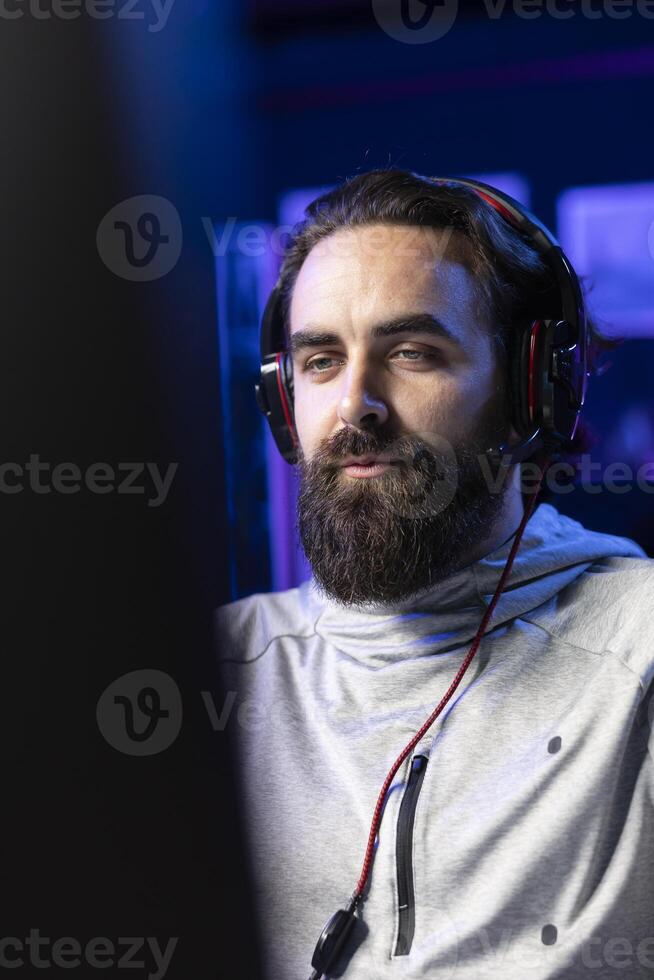 Man playing videogames in front of subscribers during livestream, focused on defeating enemies. Close up on pro gamer streaming game, wearing headphones, doing online stream photo