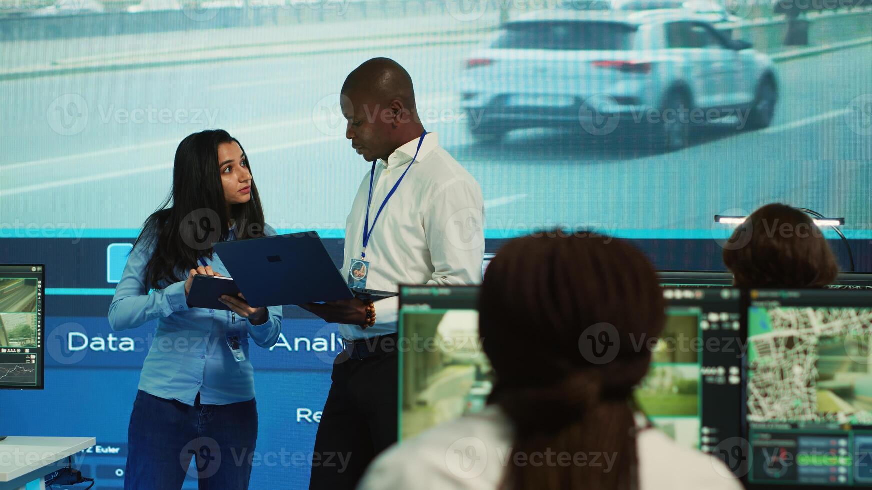 Team leaders reviewing traffic data collected from surveillance footage, monitoring urban infrastructure by using CCTV cameras system. Government agency works on public safety. Camera A. photo