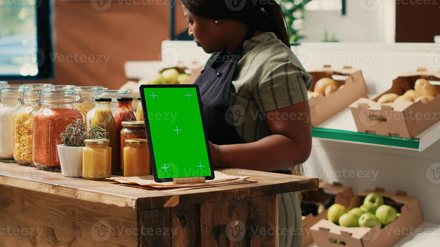 Device showing greenscreen template at local supermarket, tablet placed on store counter next to additives free sauces and pantry supplies in reusable jars. Merchant displaying copyspace screen. photo