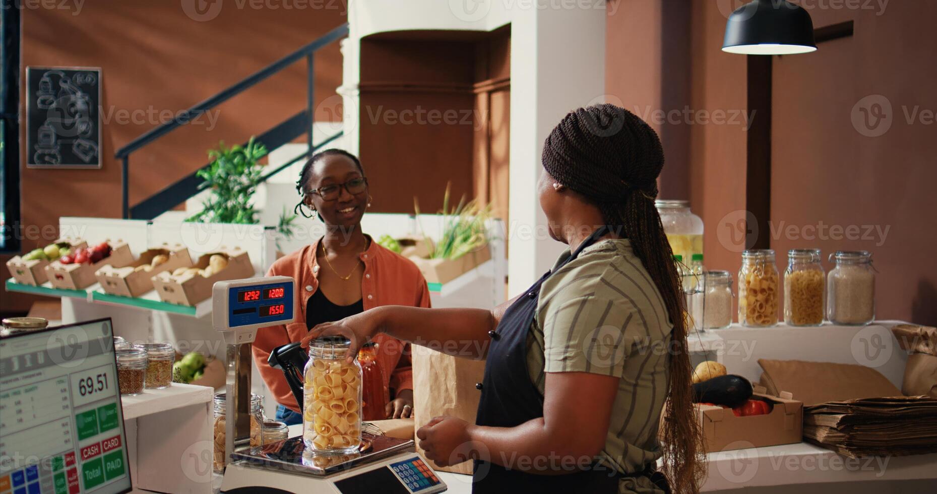 Local vendor scanning jars of organic homemade sauces at checkout, selling natural chemicals free pantry essentials. African american client buying eco friendly nonpolluting products. Handheld shot. photo