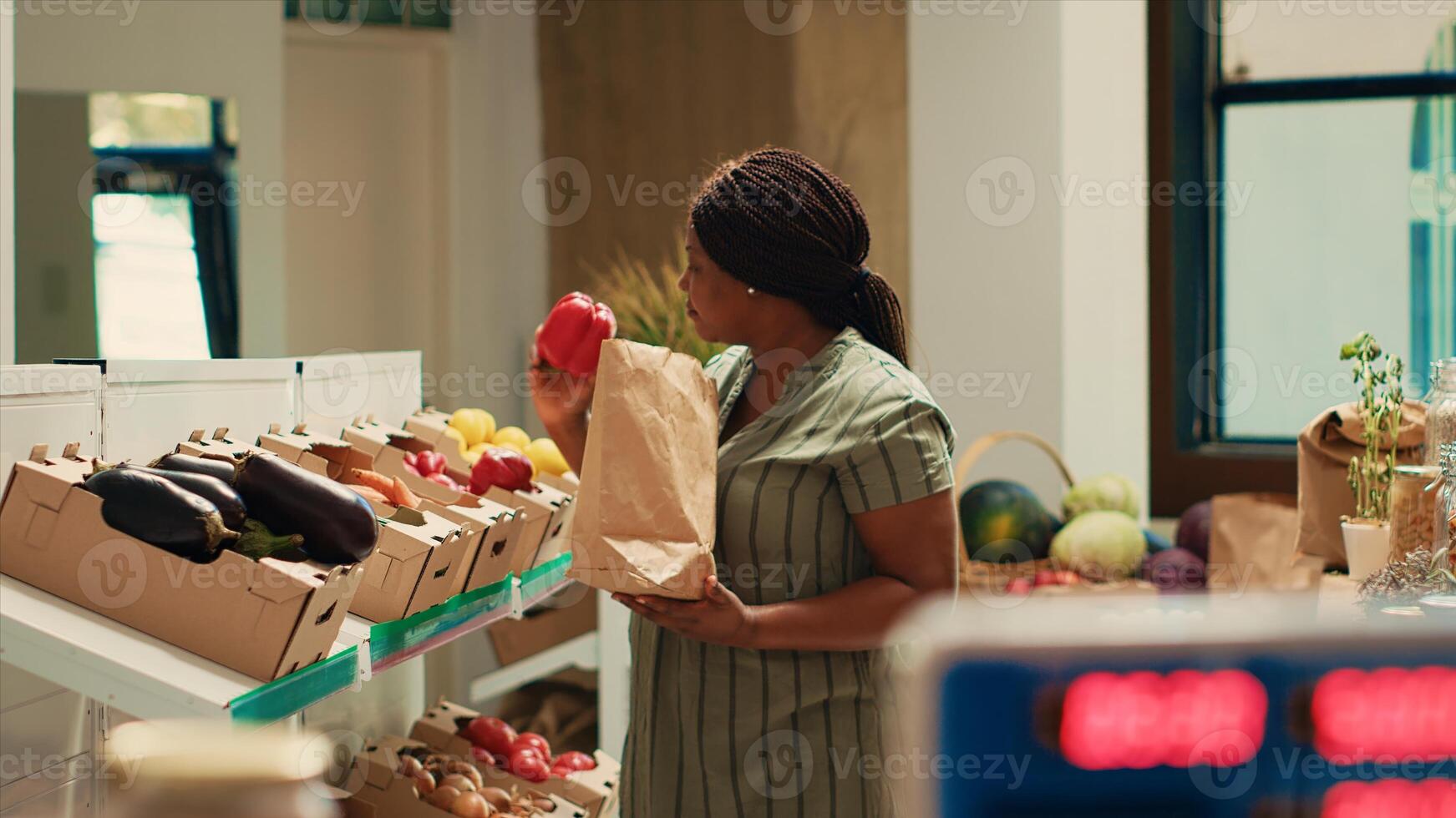 Shopper choosing natural ripe vegetables from crates, looking to buy freshly harvested veggies for a special vegan recipe. African american woman examining eco friendly produce at local store. photo
