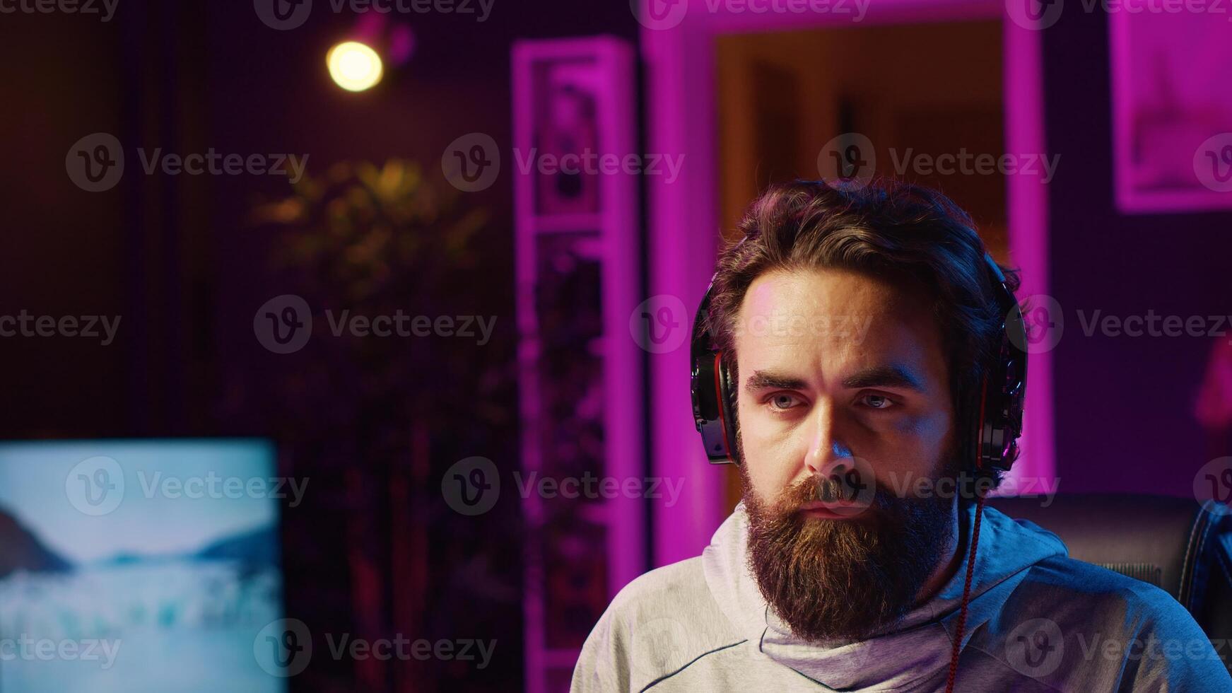Close up shot of man putting headphones on while playing videogames at home to better immerse himself. Player participating in online multiplayer esports tournament, fighting to defeat enemies photo