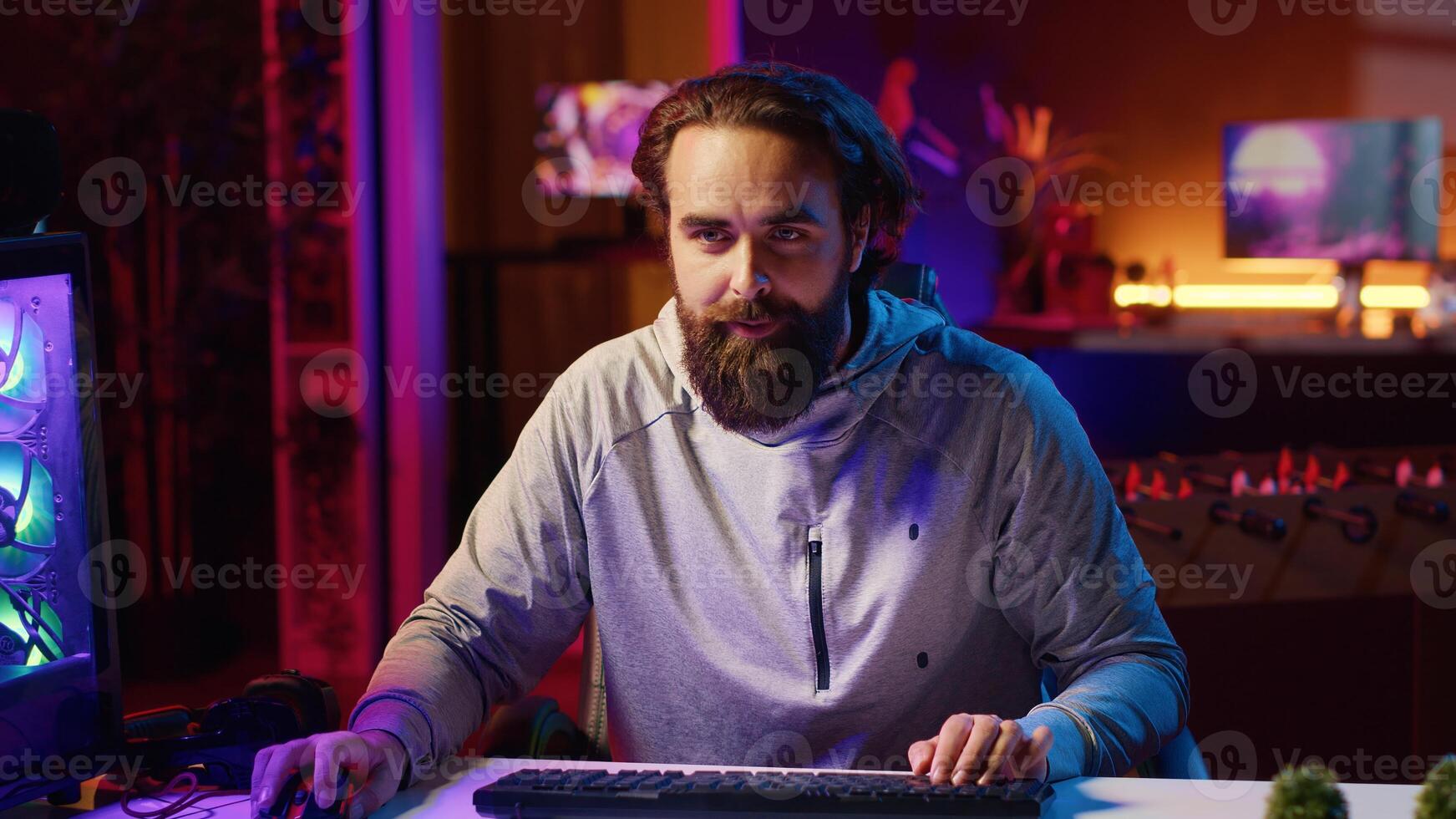 Content creator playing videogames live while chatting with online audience from neon lit apartment. Pro gamer streaming multiplayer game while discussing his strategies with viewers photo