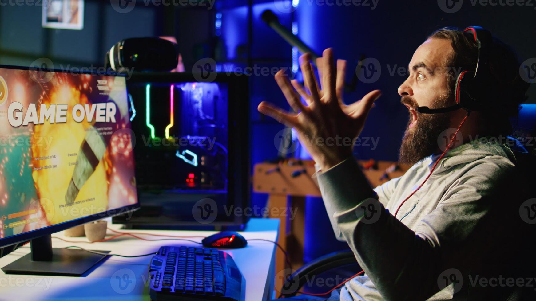 Annoyed man shouting after losing while playing online multiplayer spaceship videogame, frustrated by unhelpful teammates. Gamer raging after receiving game over message, upset with noob friends photo