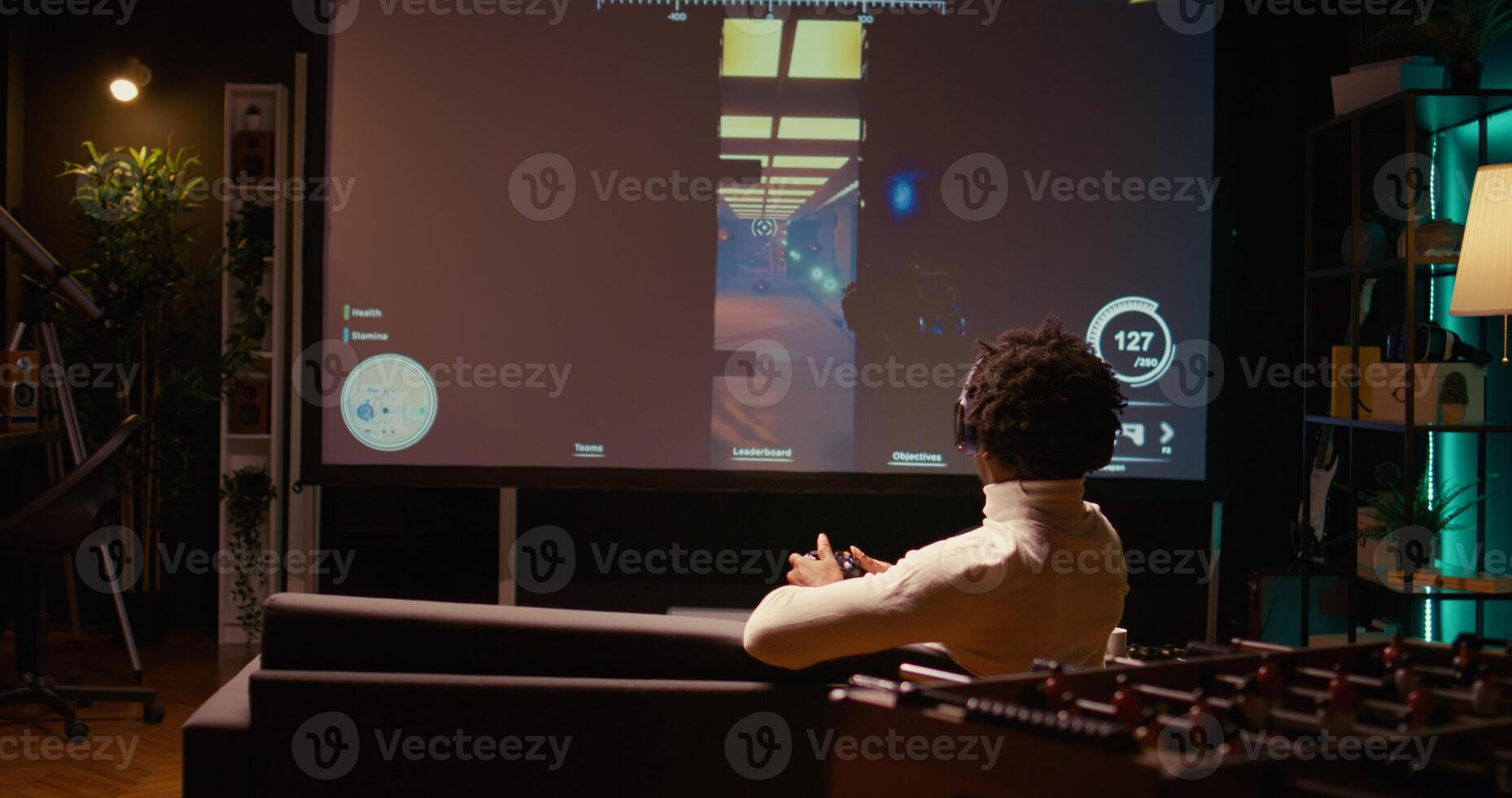 African american man playing shooter videogame on ultrawide TV with gun shooting laser bullets at flying robots. Panning shot of gamer enjoying competitive PvP fps internet multiplayer tournament game photo