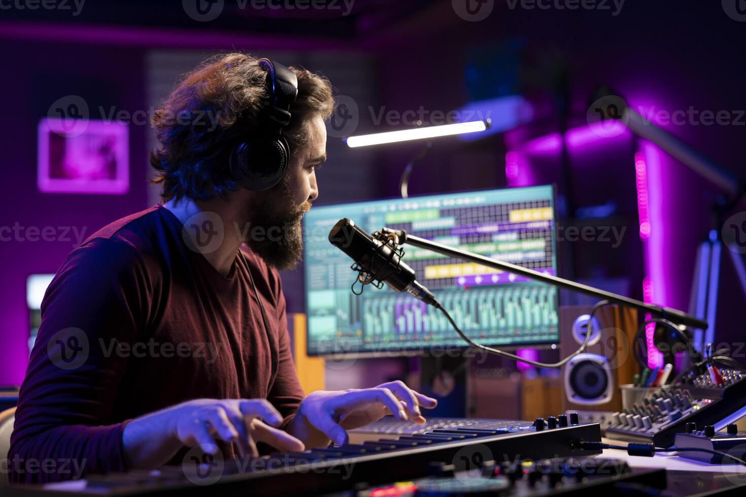 Music producer singing song on microphone and playing piano keyboard to record tunes on aw software interface. Artist creating soundtracks with audio equipment, midi controller gear. photo