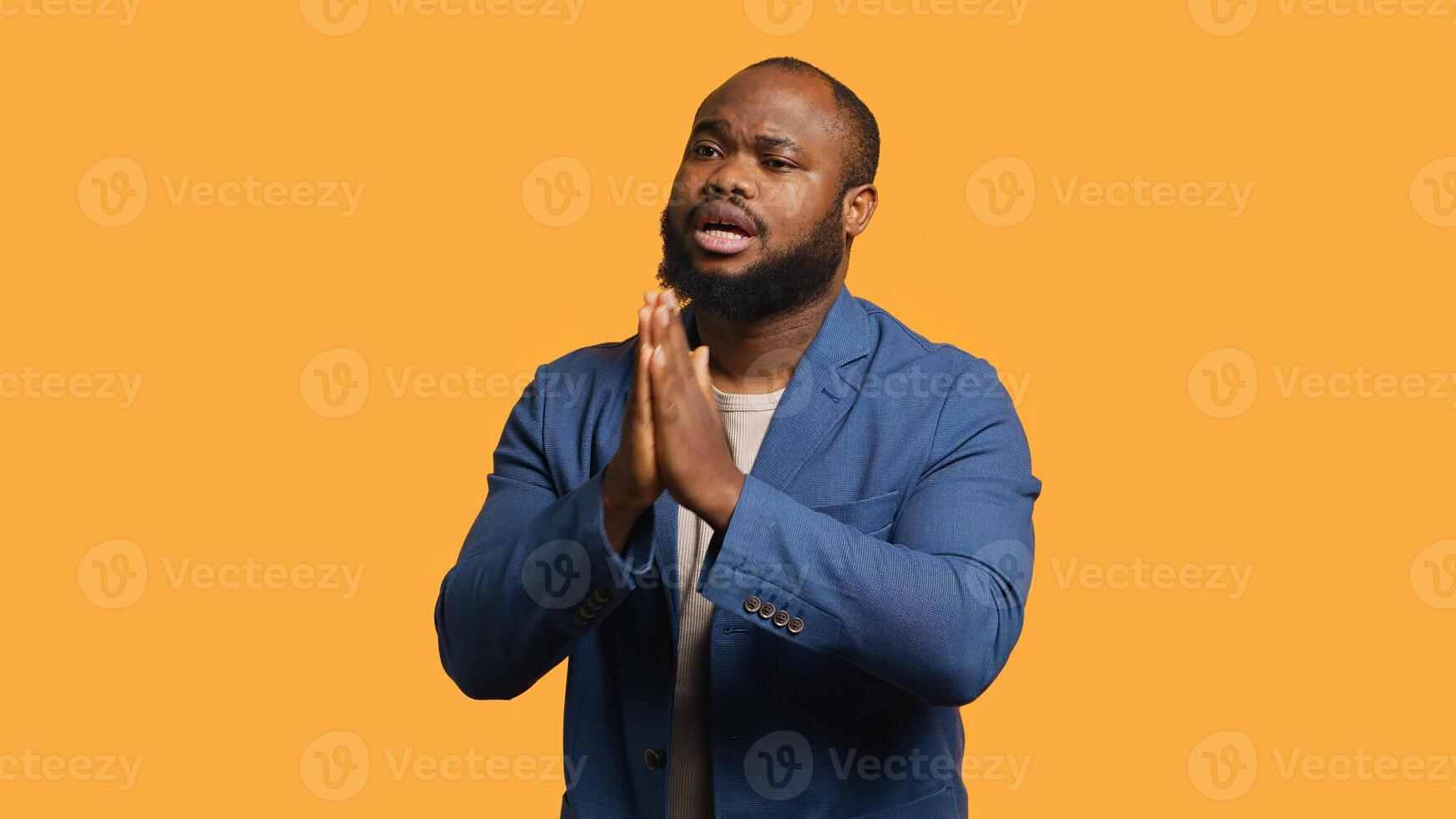Friendly african american man puts hands together in apology gesture, asking for forgiveness. Apologetic BIPOC man doing sorry gesturing, asking for pardon, isolated over studio background, camera A photo