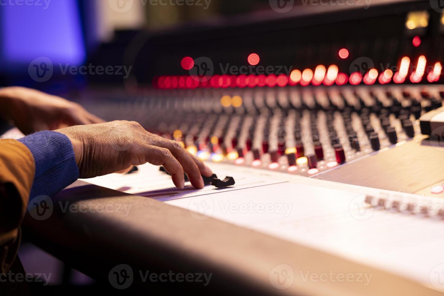 Audio expert recording and editing music with mixing console panel board, twisting knobs and changing sound settings in studio. Music producer working in control room. Close up. photo
