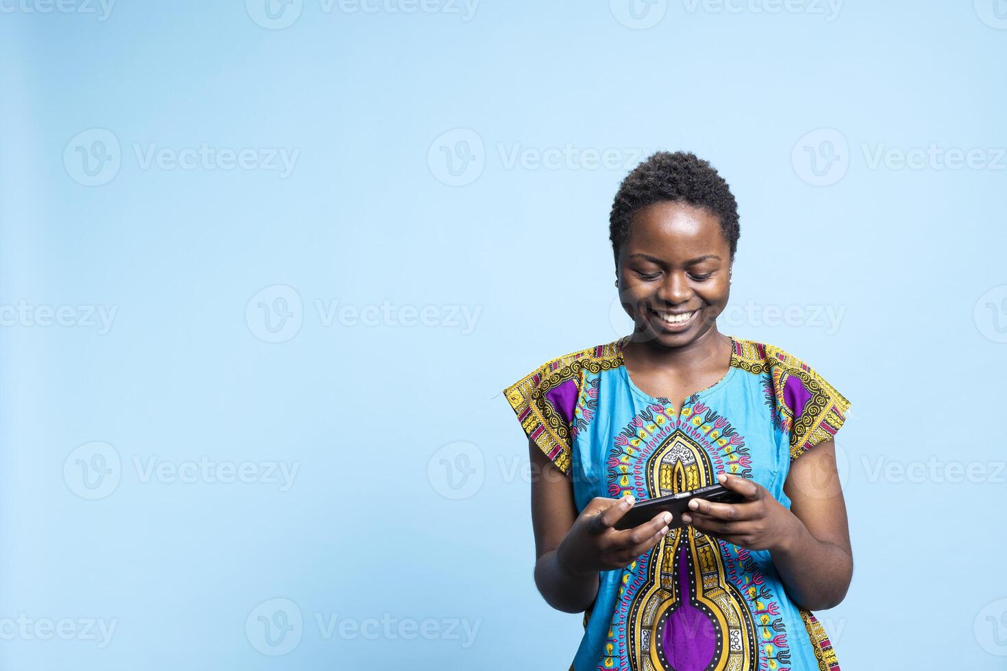 African american girl playing mobile videogames on smartphone, feeling happy and joyful in front of camera. Modern person having fun with online gaming challenge, e sport leisure. photo
