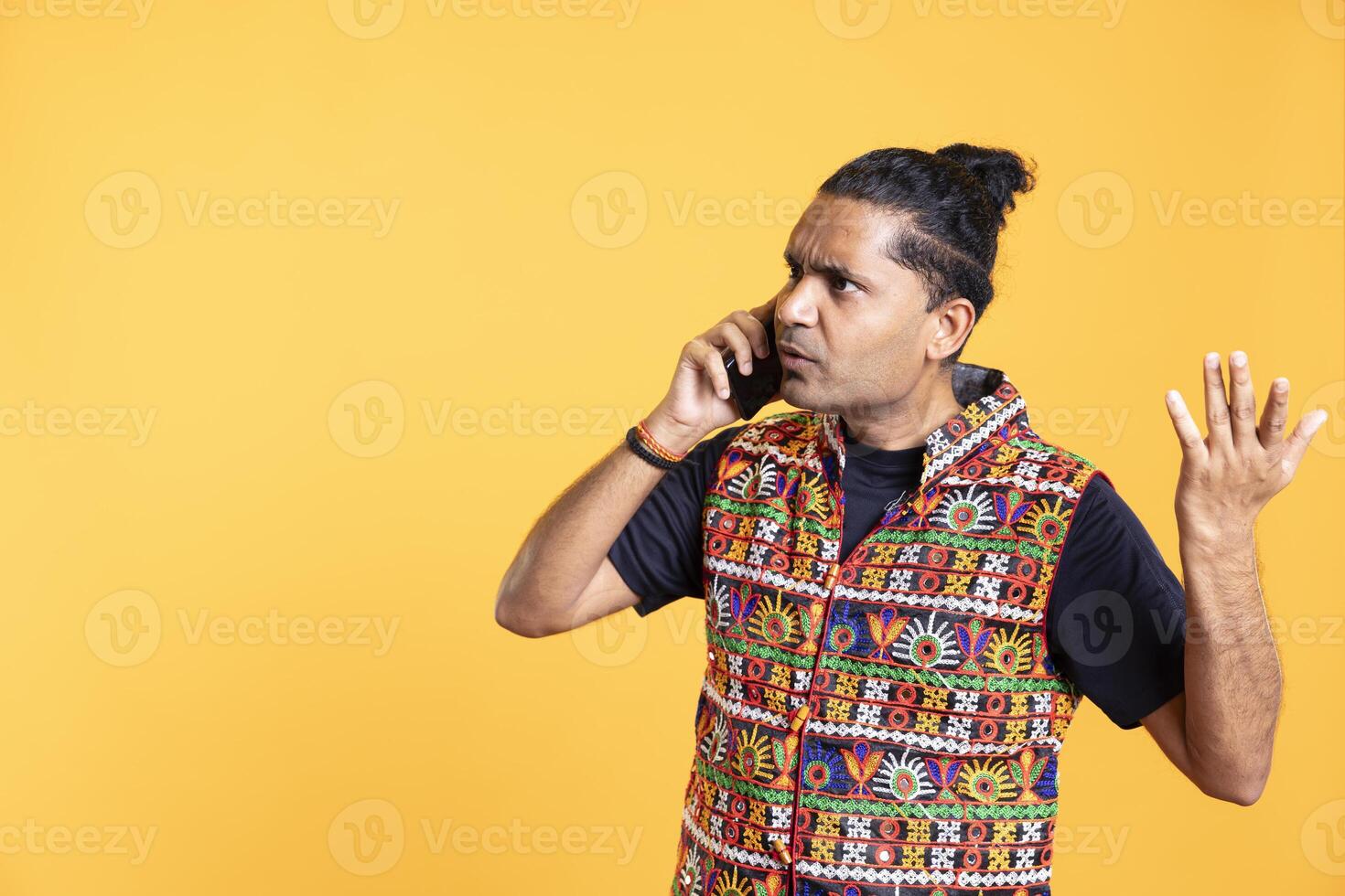 Disappointed indian man admonishing friend over debacle on call, negatively surprised by him, studio background. Upset person in disagreement with mate, rejecting arguments from his opponent photo