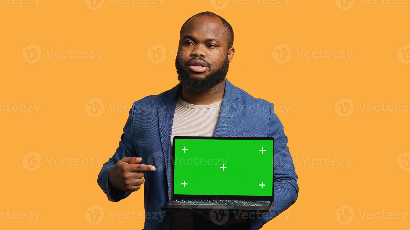 Jolly african american man holding green screen laptop, doing recommendation. Friendly BIPOC person pointing towards mockup notebook, giving positive feedback, studio background, camera A photo