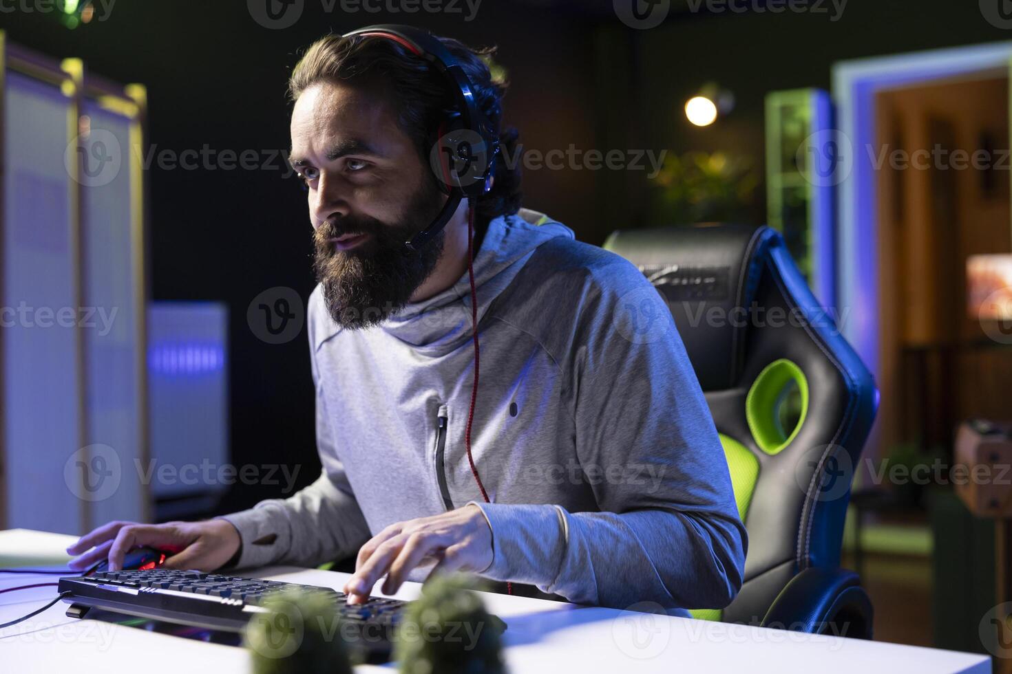 Man powering up computer to play videogames after arriving home in neon lit apartment, ready to have fun and relax with his online friends. Gamer sitting down on gaming chair, joining teammates photo
