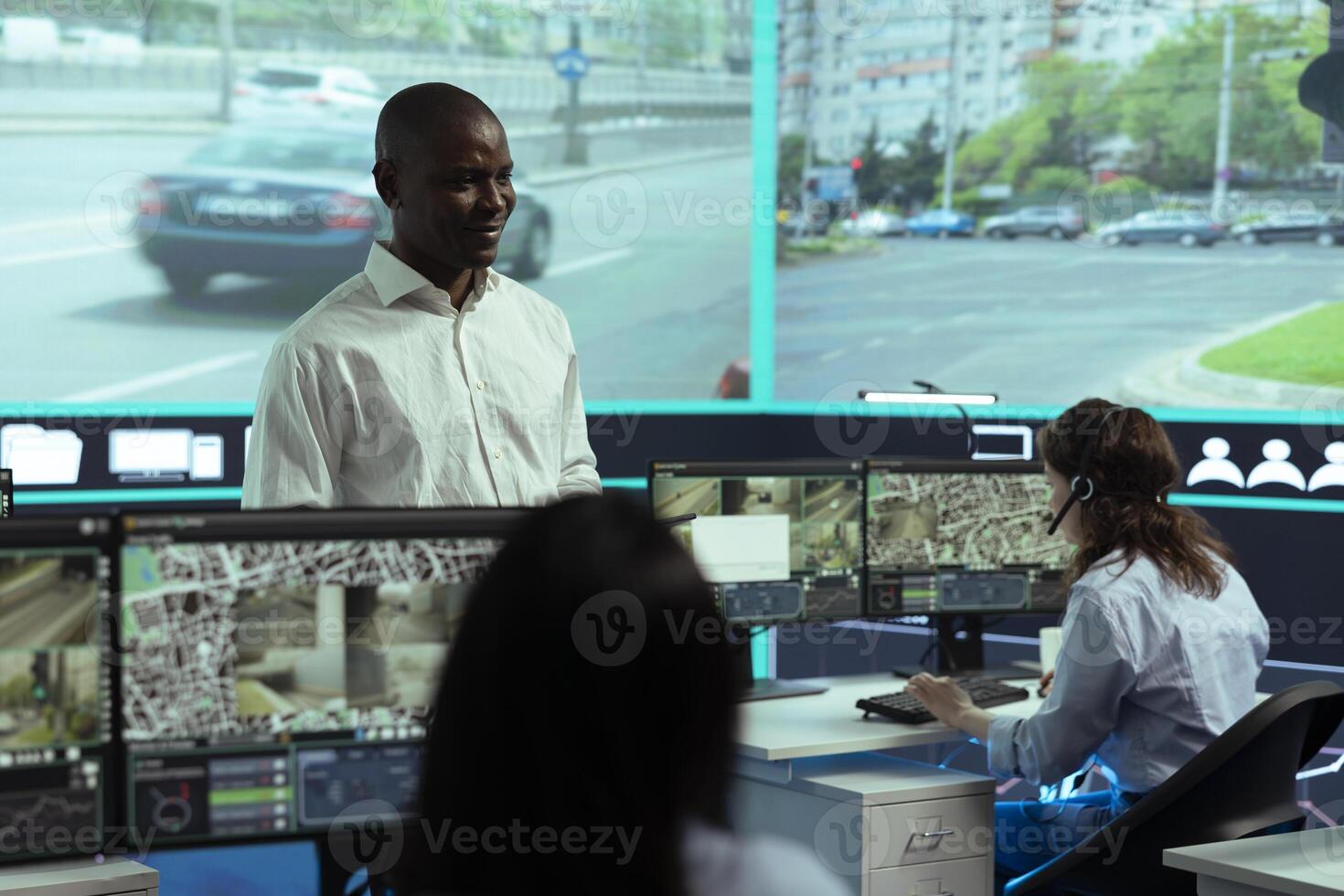 African american manager leads his staff to monitor the surveillance footage on CCTV system to learn about urban traffic dynamics. Diverse team working on public safety, satellite radar. photo